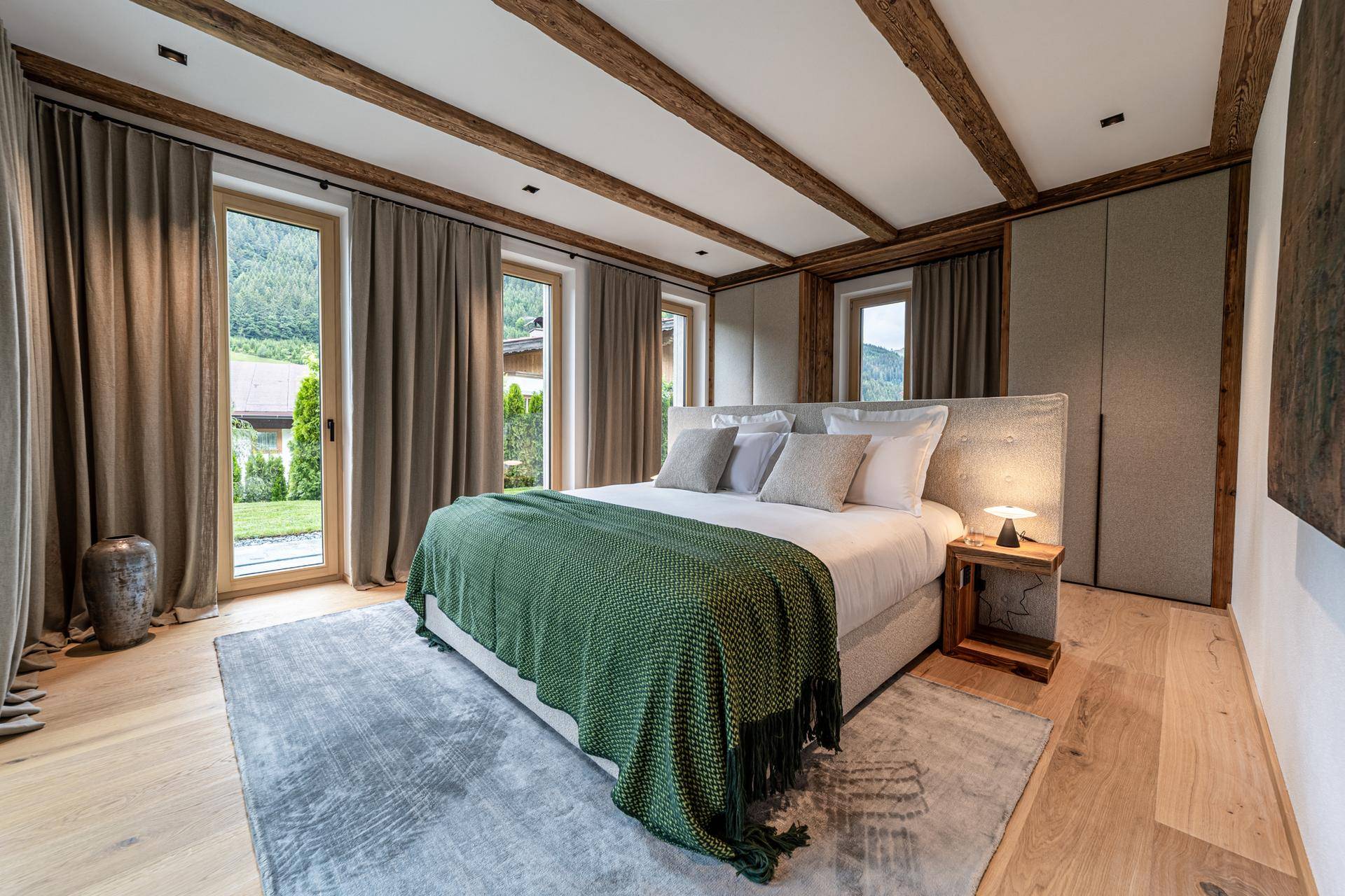 Gemütliches Schlafzimmer mit Holzbalken, großem Bett und direktem Zugang zum Gartenbereich.