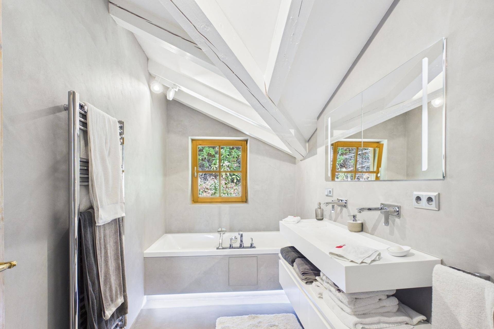 Modernes Badezimmer im Dachgeschoss mit Badewanne, Doppelwaschbecken und beheiztem Handtuchhalter.