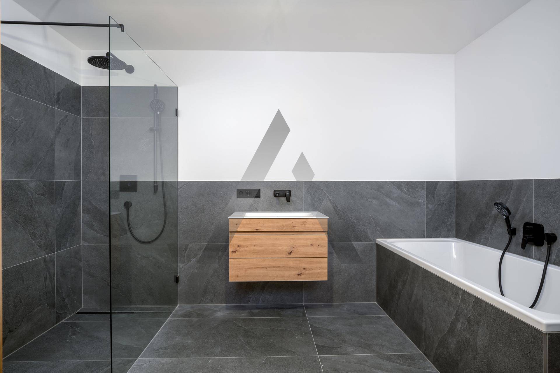 Modernes Badezimmer mit großen grauen Fliesen, begehbarer Dusche und Badewanne.