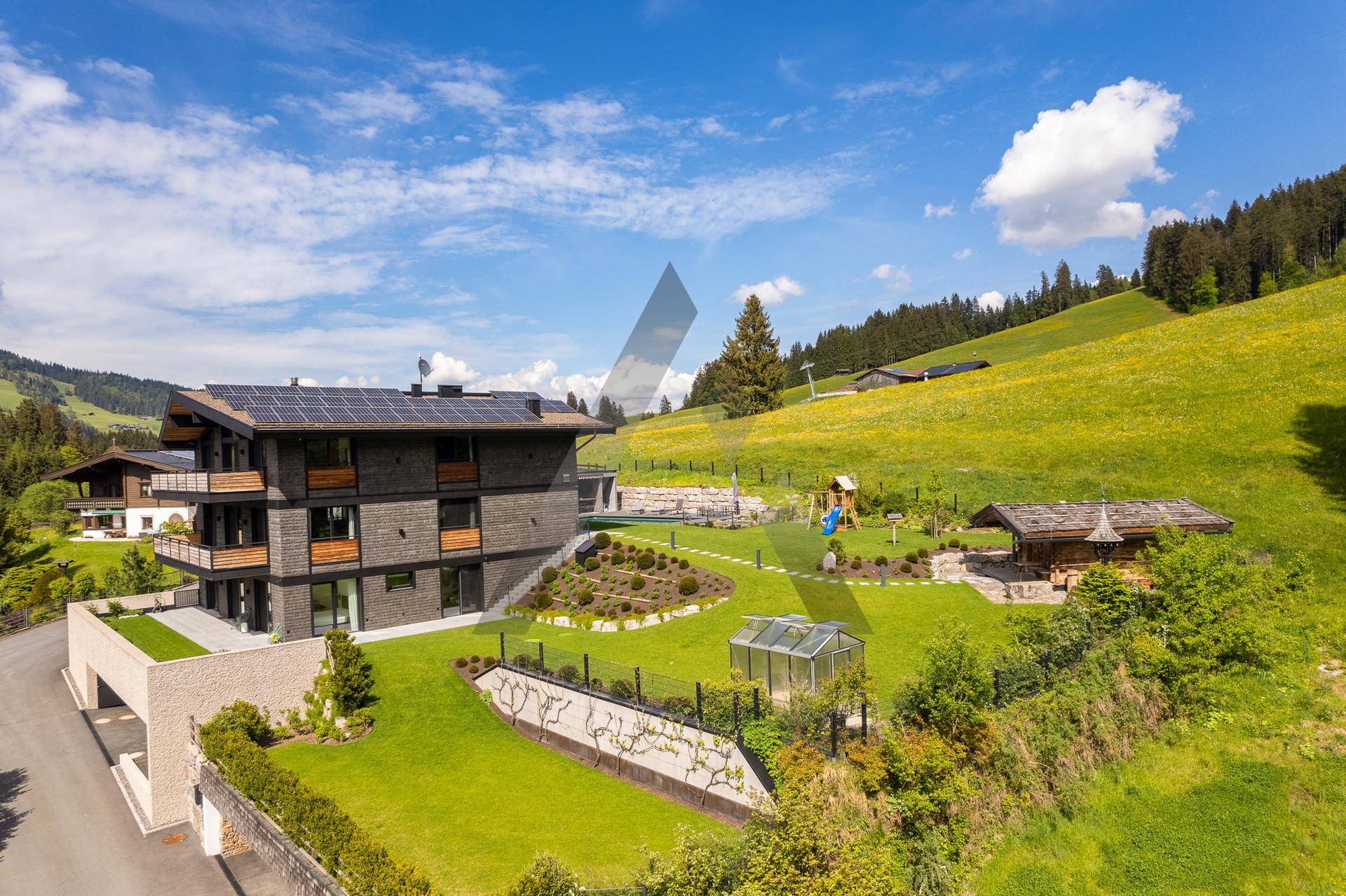Weitläufiges Anwesen mit modernem Haus, großem Garten, Spielplatz und Bergblick.