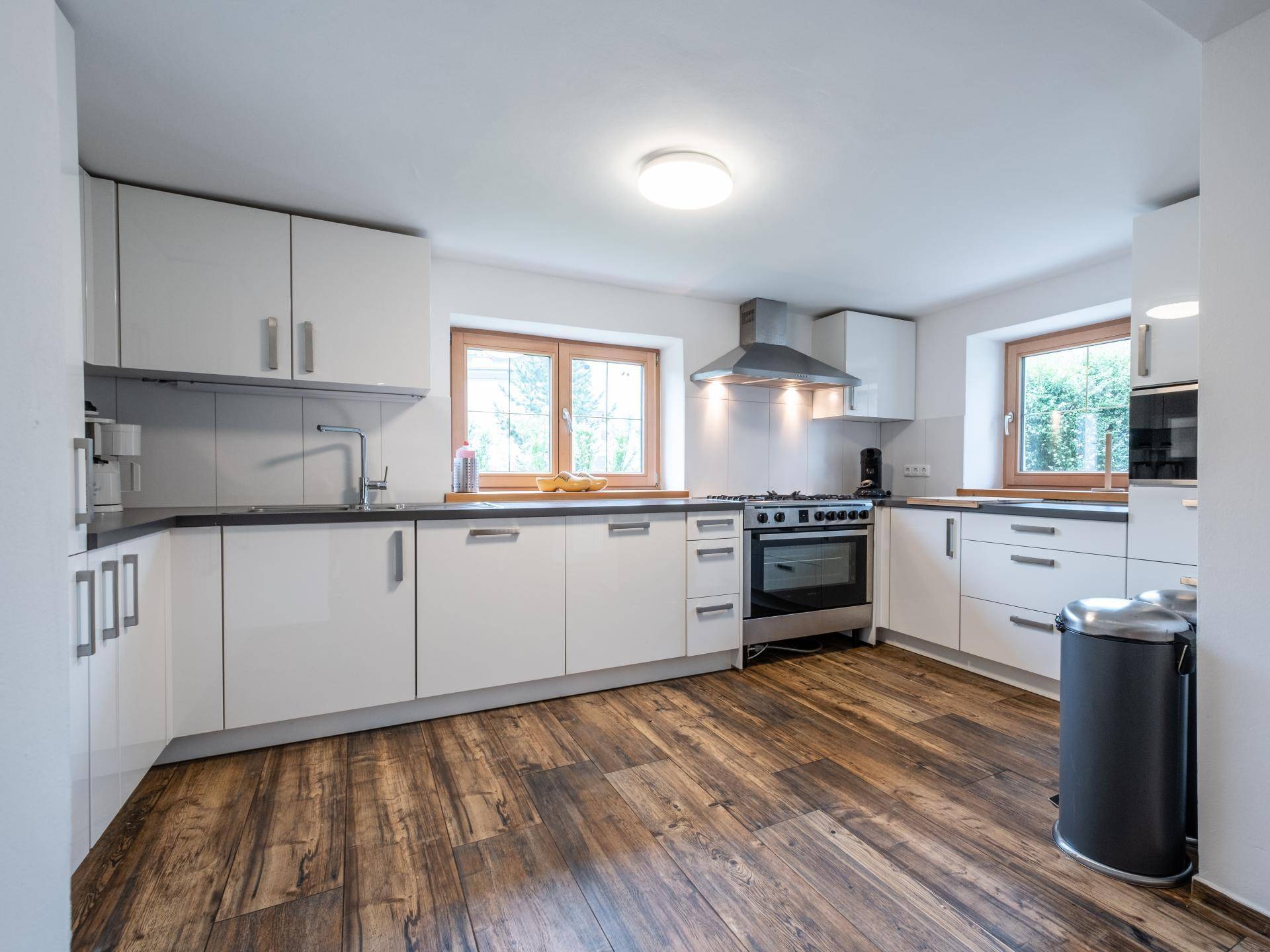 Moderne Küche mit weißen Hochglanzschränken, dunkler Arbeitsplatte und Gasherd, ausgestattet mit Laminatboden.
