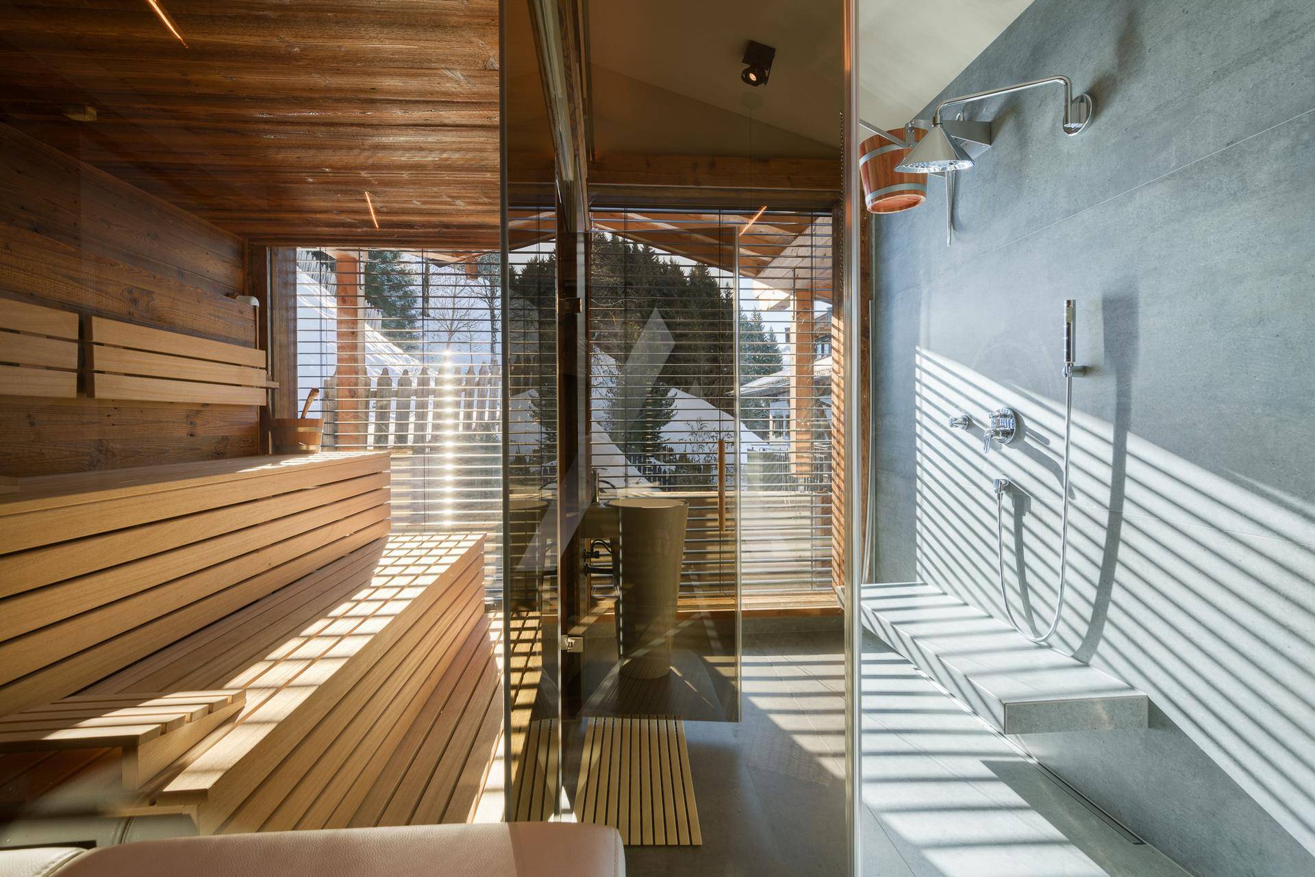 Moderne Sauna mit Holzbänken, Glasfront und Blick auf die Natur.