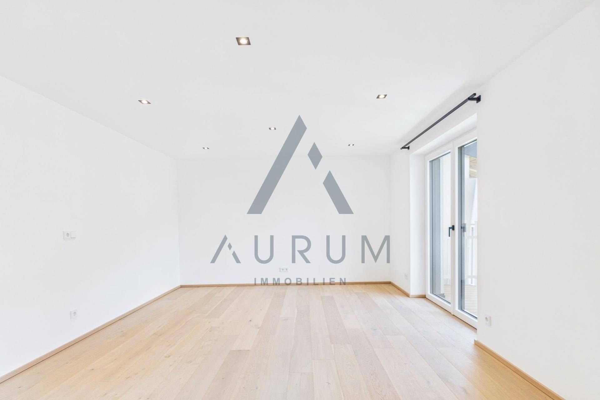 Geräumiges, helles Wohnzimmer mit Holzboden und Zugang zu einem Balkon.