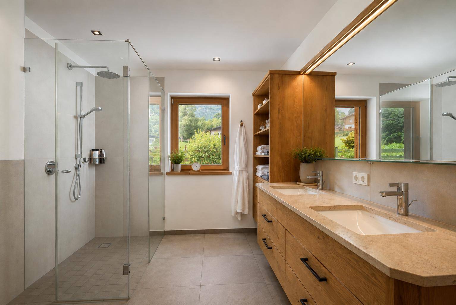 Großes Badezimmer mit Doppelwaschbecken, begehbarer Dusche und Fenster mit Blick ins Grüne.