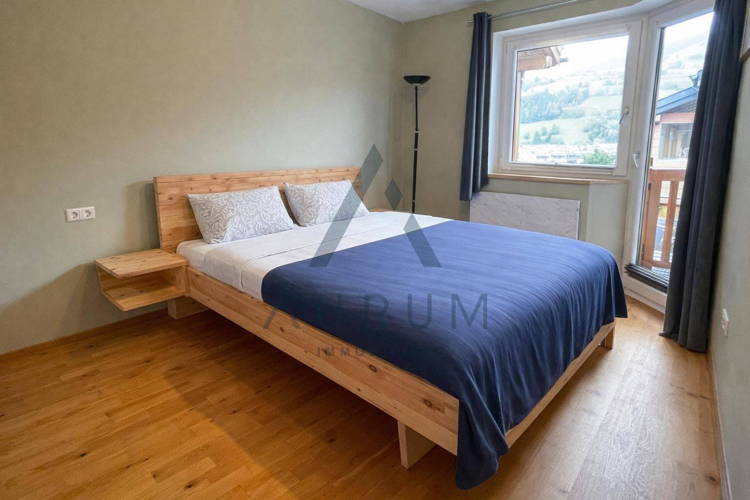 Helles Schlafzimmer mit Holzbett, Parkettboden und direktem Zugang zum Balkon.