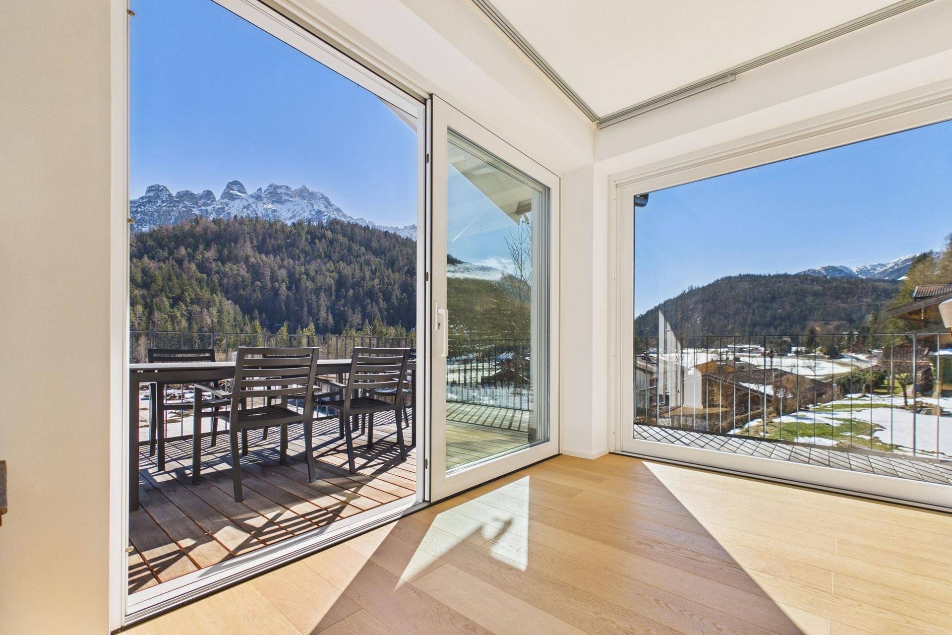 Heller Raum mit großen Schiebetüren, die zu einem Balkon mit Bergblick führen.
