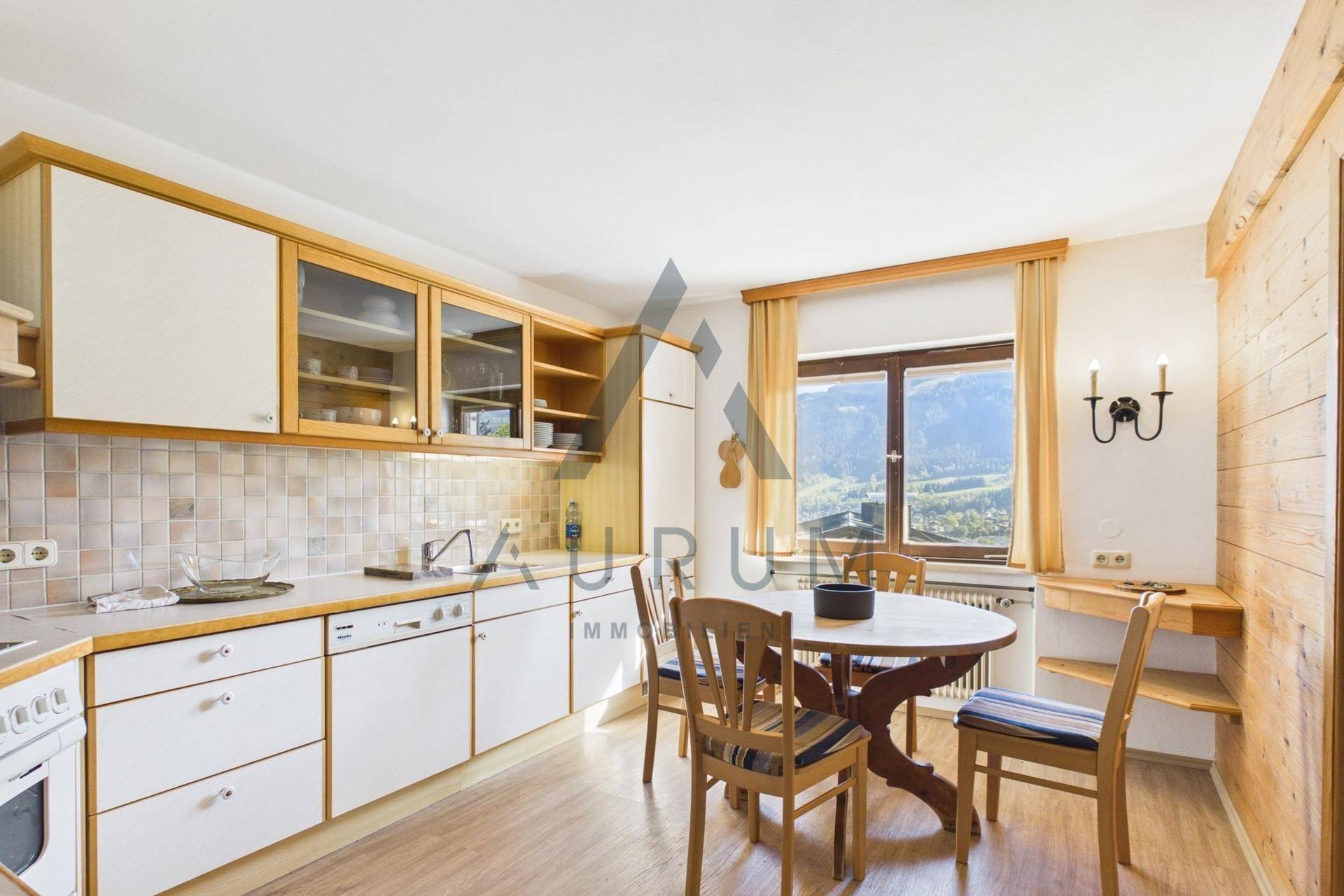 Gemütliche Küche mit Holzelementen, Essbereich und Bergblick durch das Fenster.