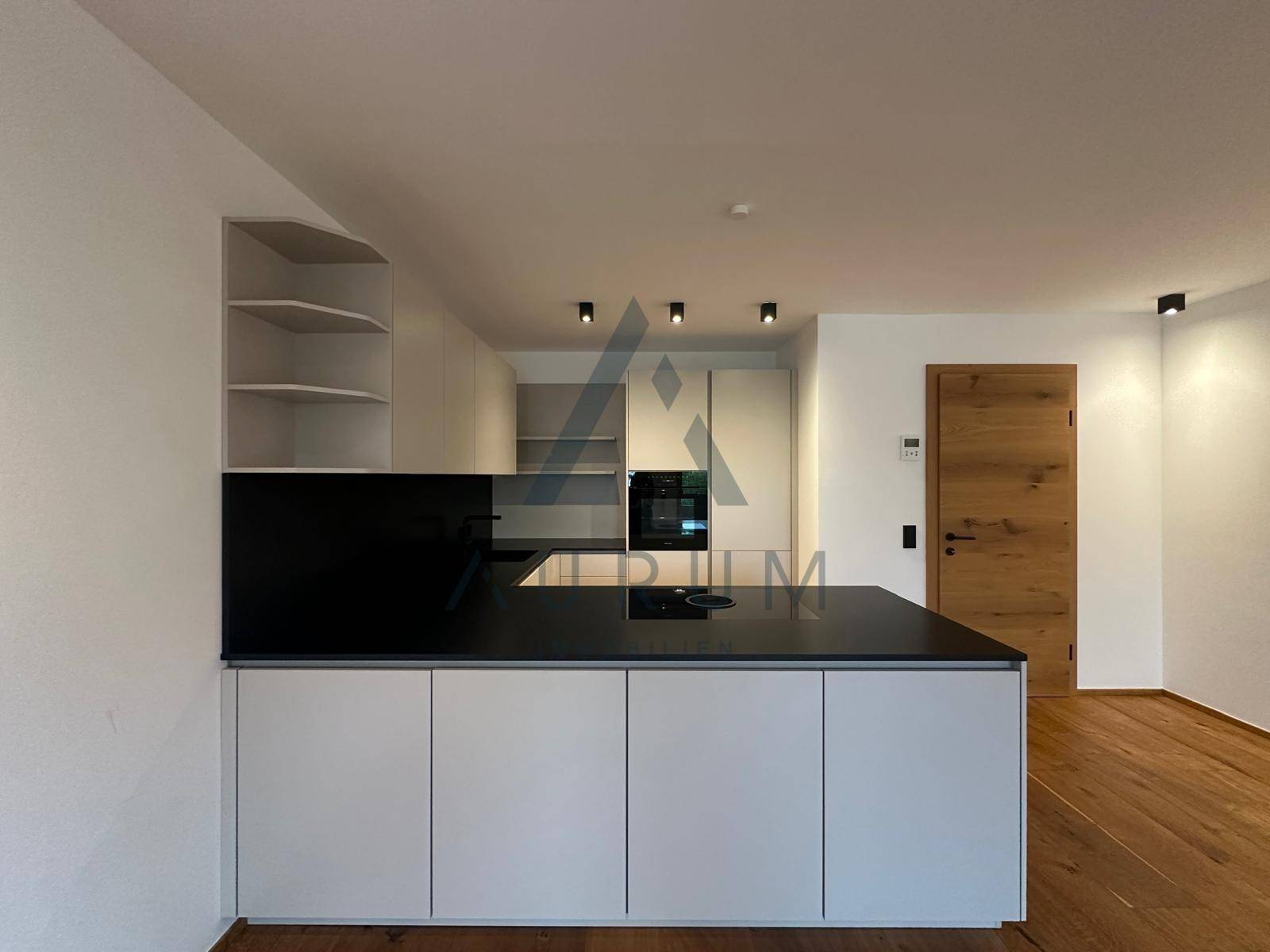 Detailansicht der modernen Einbauküche mit Kochfeld auf der Insel und Holzdetails.
