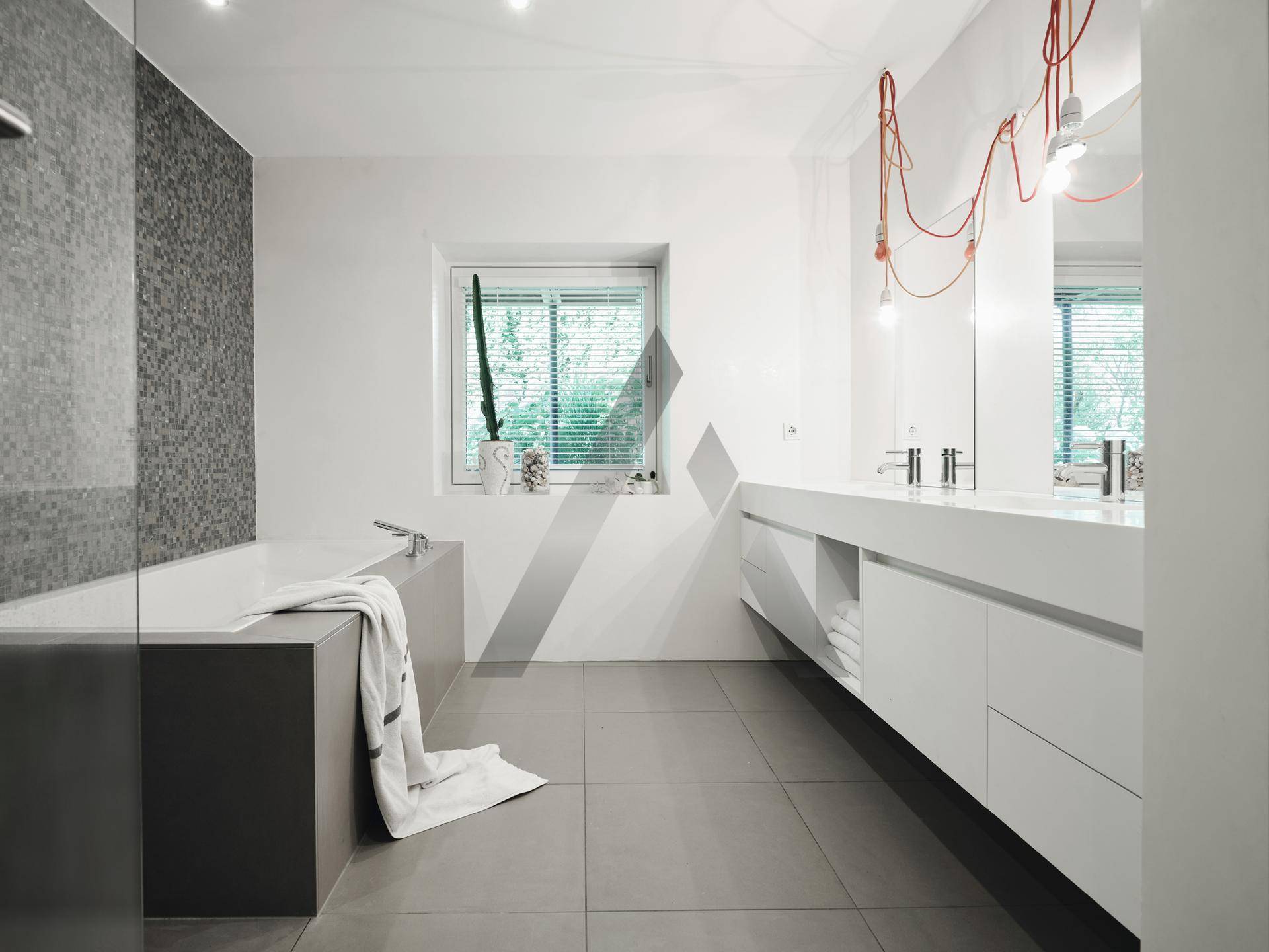 Modernes Badezimmer mit Doppelwaschbecken, Badewanne und Fenster für Tageslicht.