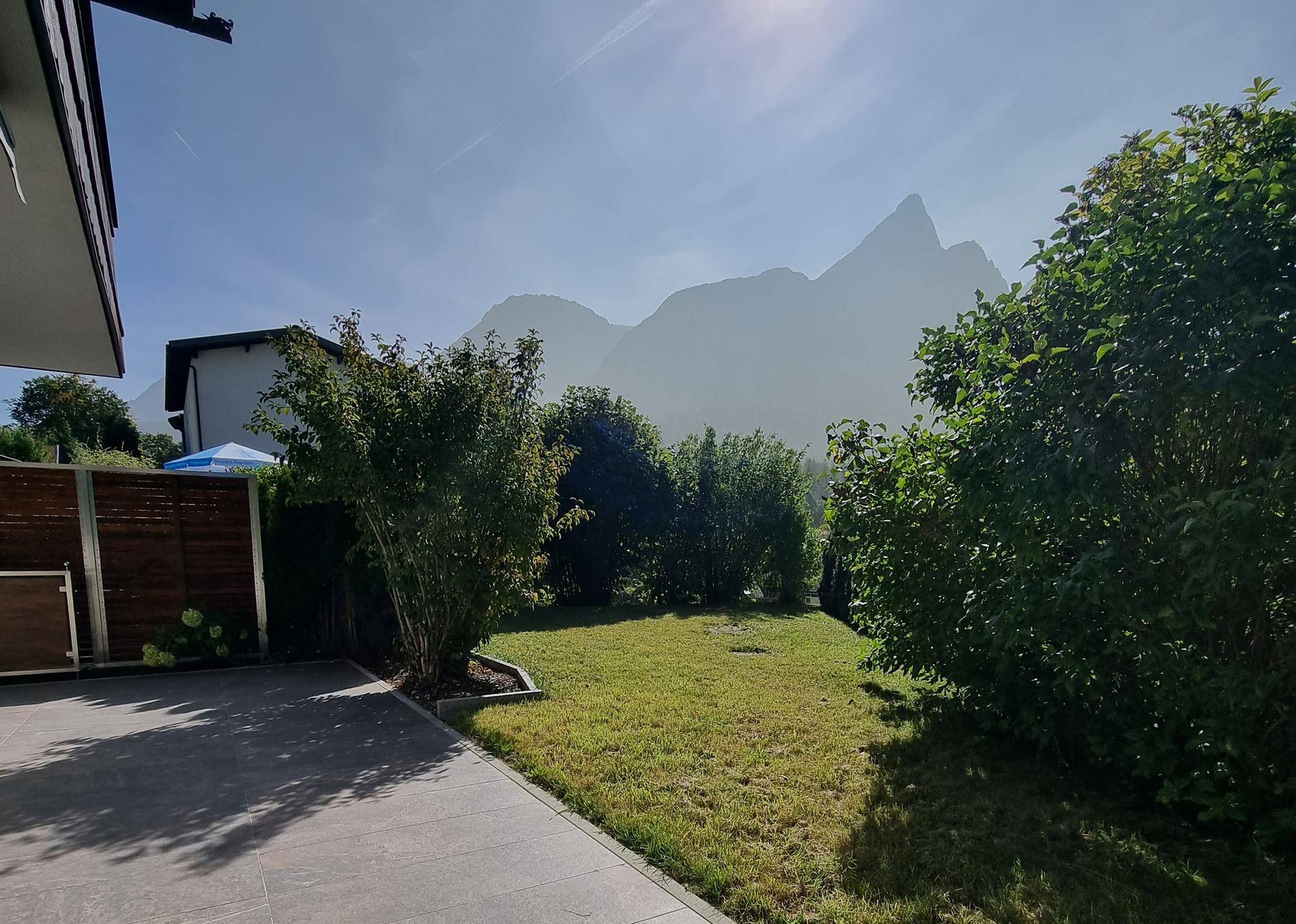 Gepflegter Gartenbereich mit Rasenfläche und weitem Blick auf die umliegenden Berge.
