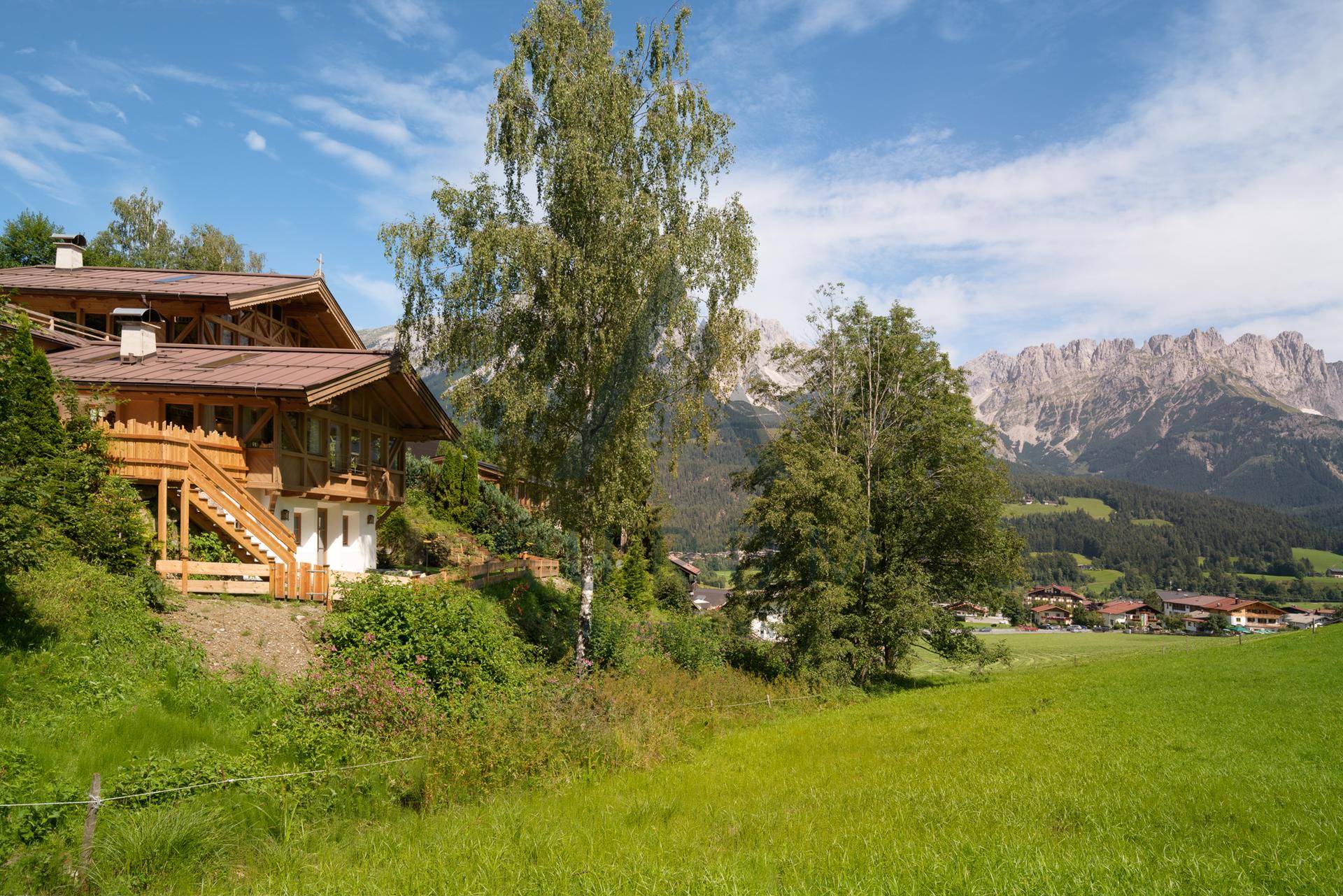 Idyllisches Anwesen in alpiner Landschaft mit weiten Wiesen und majestätischem Bergpanorama.