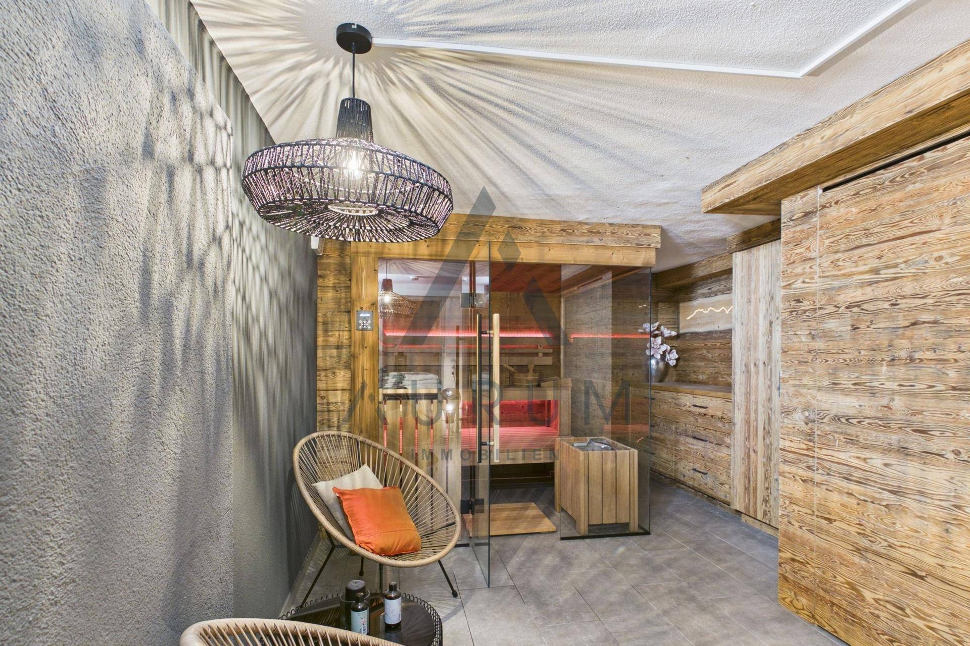 Entspannender Wellnessbereich mit Sauna, bequemen Korbsesseln und Holzakzenten.