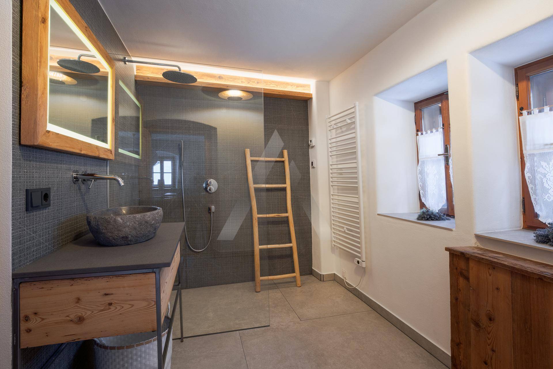 Modernes Badezimmer mit begehbarer Dusche, Steinwaschbecken und beheiztem Handtuchhalter.