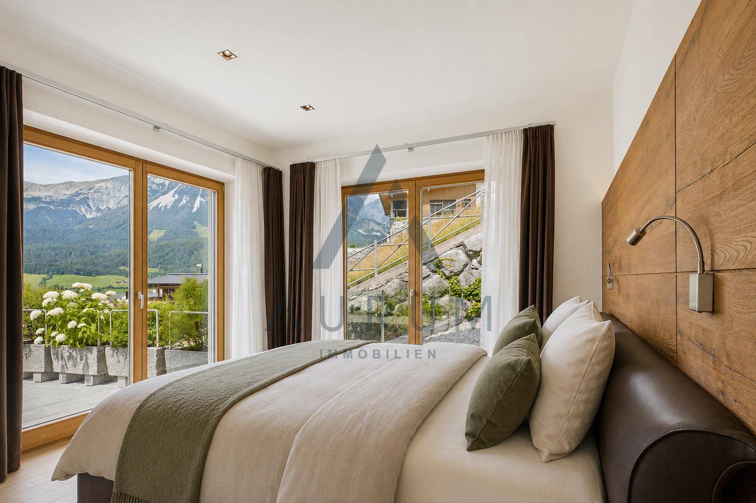 Gemütliches Schlafzimmer mit Holzwand, großem Bett und Zugang zu einer Außenterrasse.