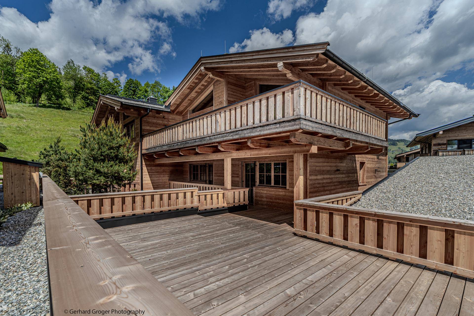 Attraktives Holzchalet mit großzügiger Terrasse und Balkon, eingebettet in eine grüne Umgebung.