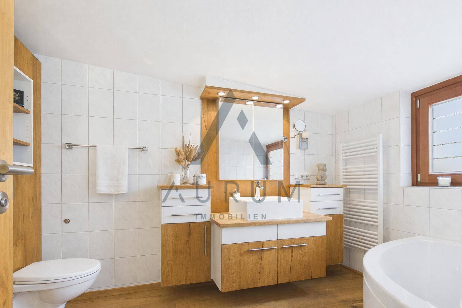 Geräumiges Badezimmer mit Badewanne, großem Waschtisch, Spiegel und weißen Wandfliesen.