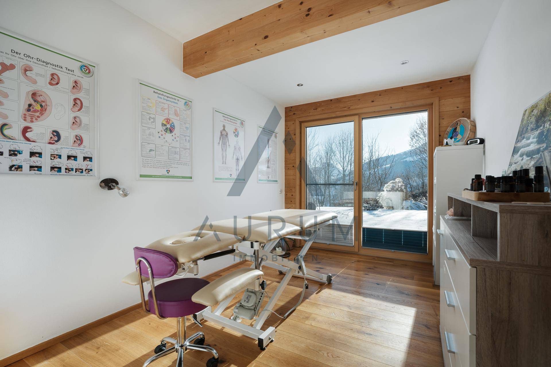 Heller Raum, eingerichtet als Büro oder Therapiezimmer, mit Holzbalken und Bergblick.
