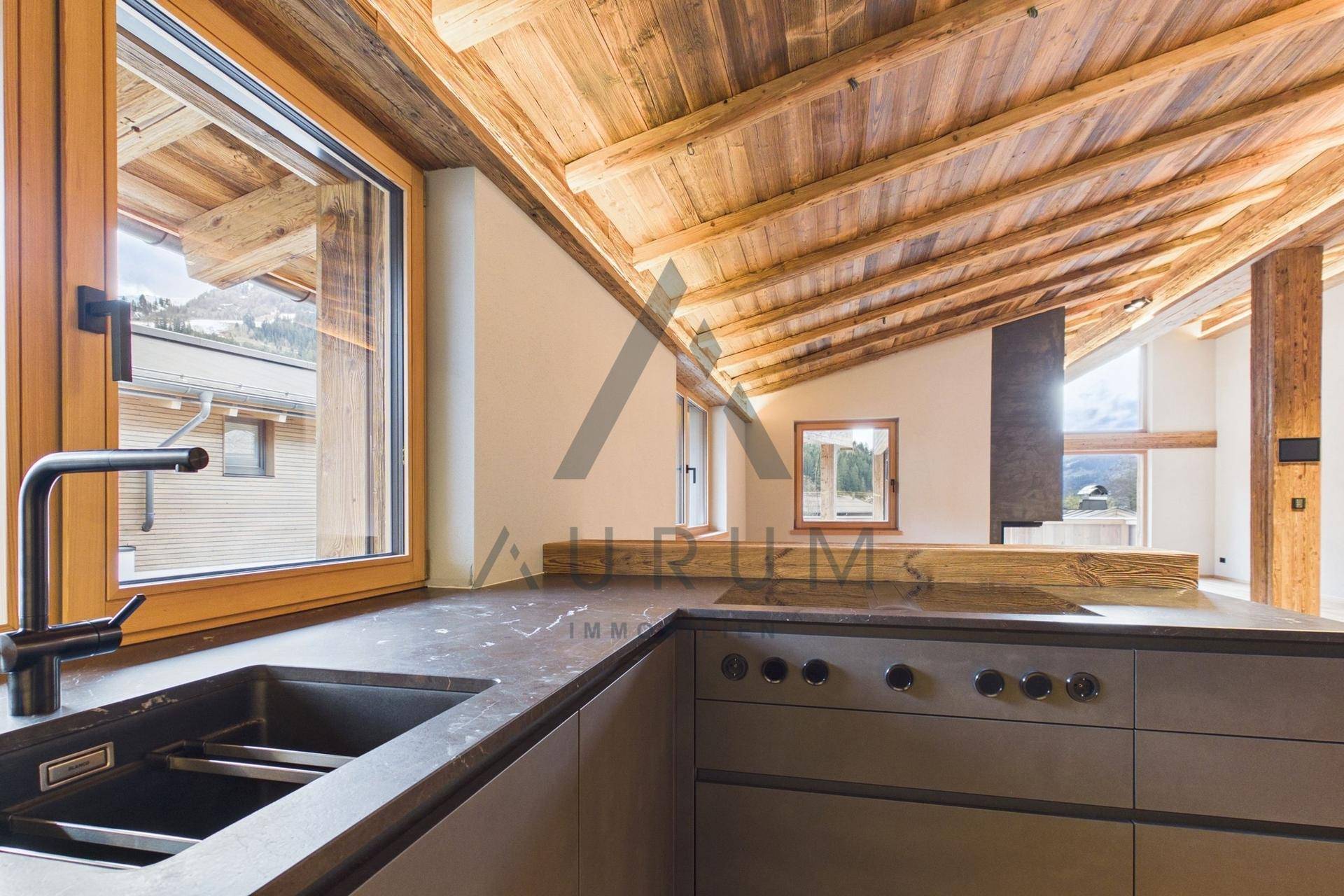 Offener Küchenbereich mit Spüle und Blick in einen angrenzenden Wohnraum mit modernem Kamin.