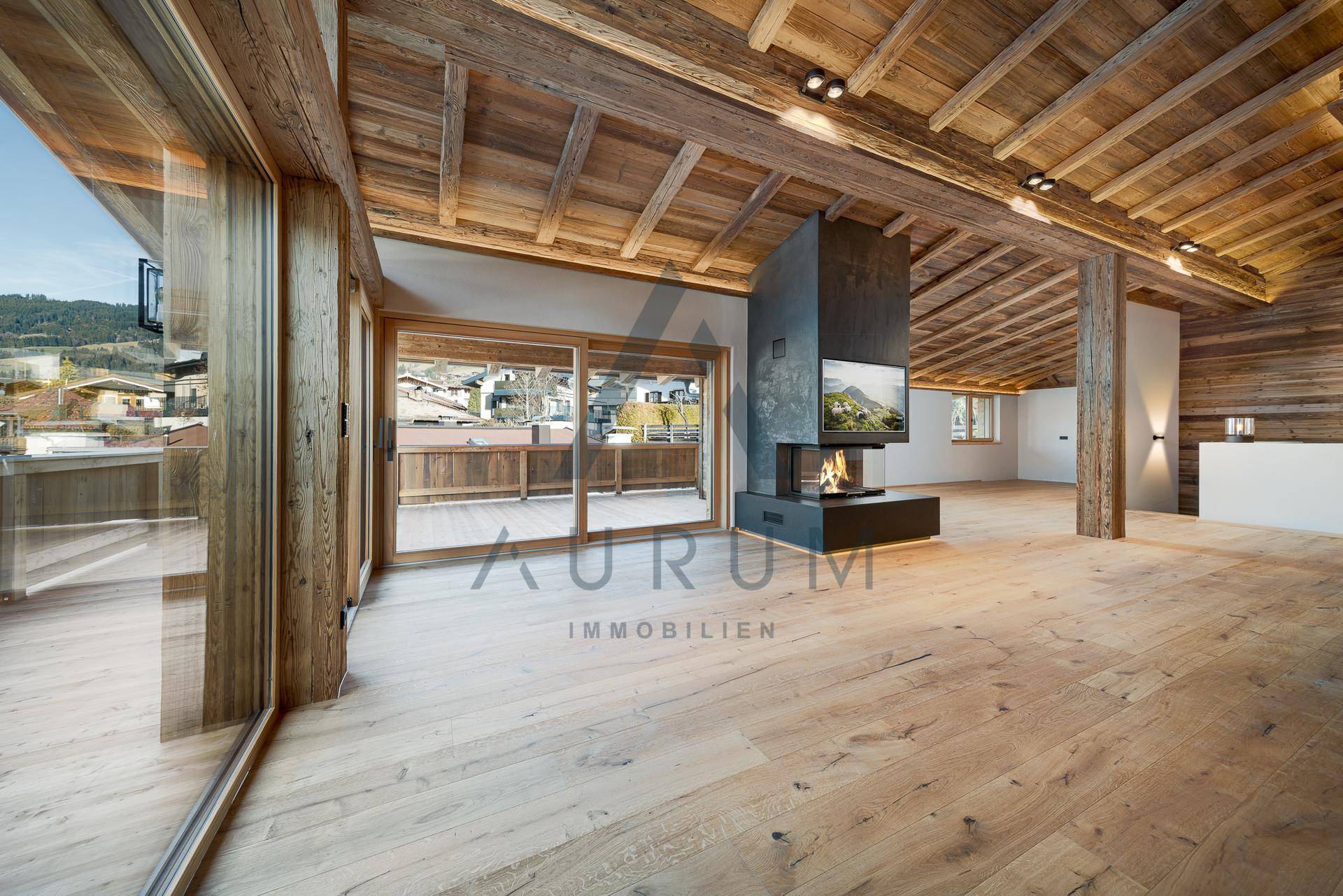 Geräumiges Wohnzimmer mit Holzboden, freistehendem Kamin und Zugang zu einer großen Terrasse.
