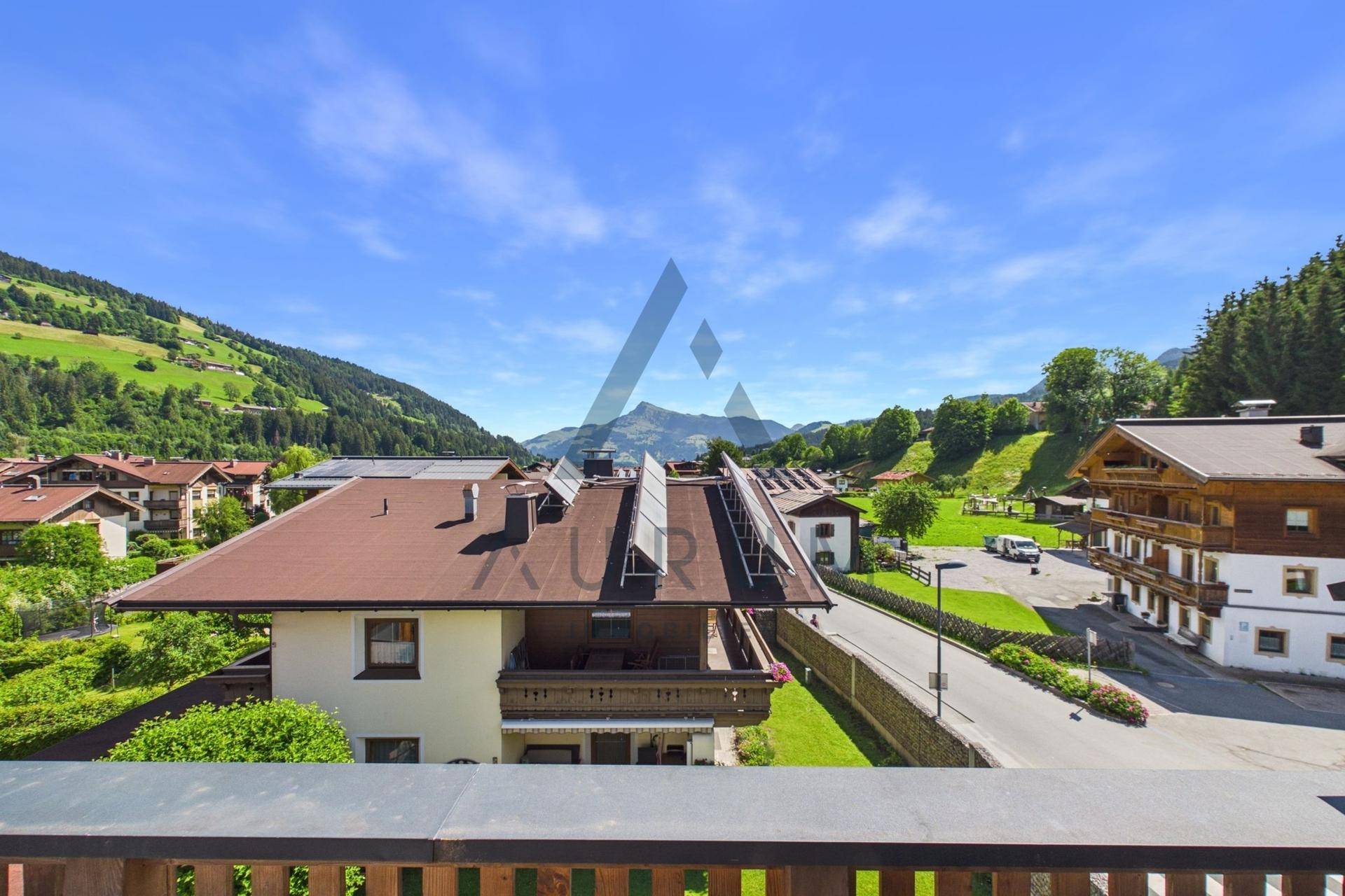 Panoramablick auf die alpine Umgebung mit Wohnhäusern und grünen Hügeln.