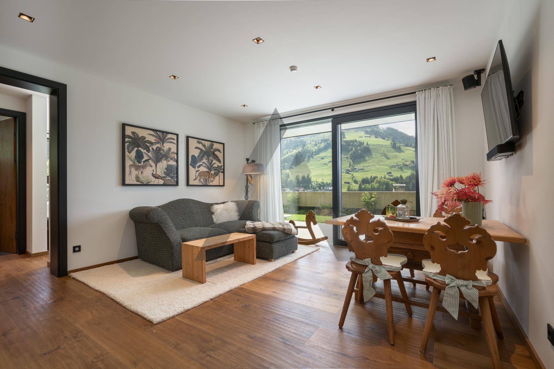 Gemütlicher Wohn- und Essbereich mit Holzboden und traditionellen Holzstühlen.