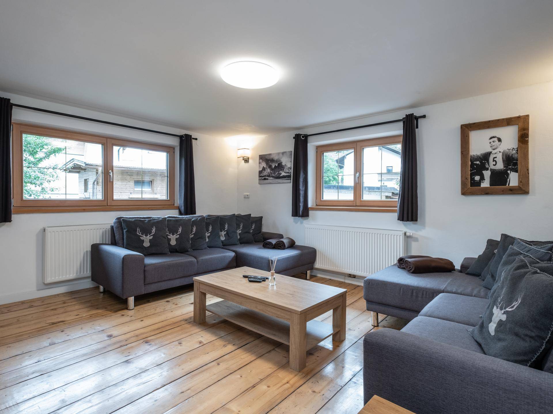 Gemütliches Wohnzimmer mit zwei großen grauen Sofas, Holztisch und breiten Dielenböden.