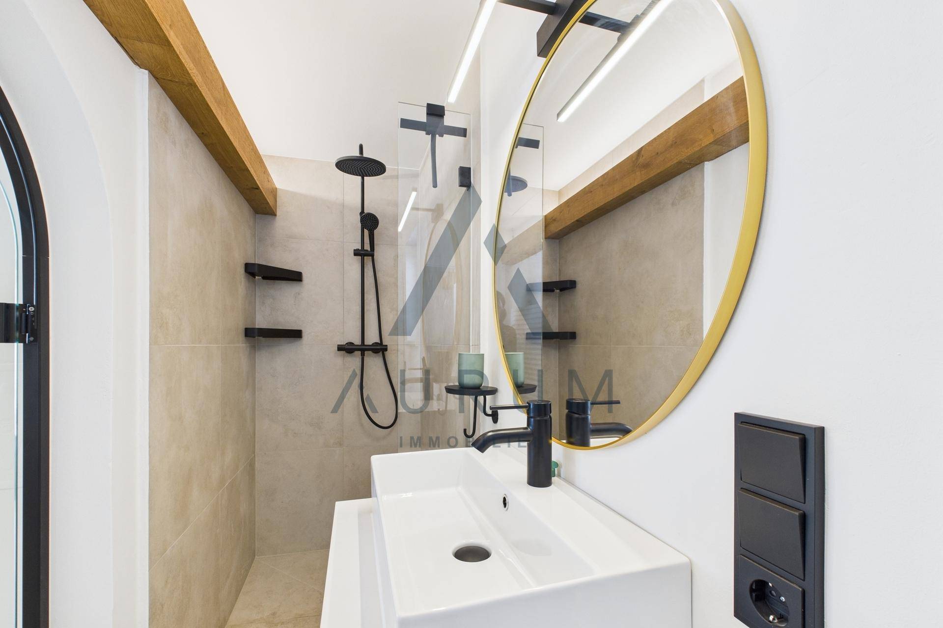 Detailansicht des modernen Badezimmers mit stilvollem Spiegel, Waschtisch und Regendusche.