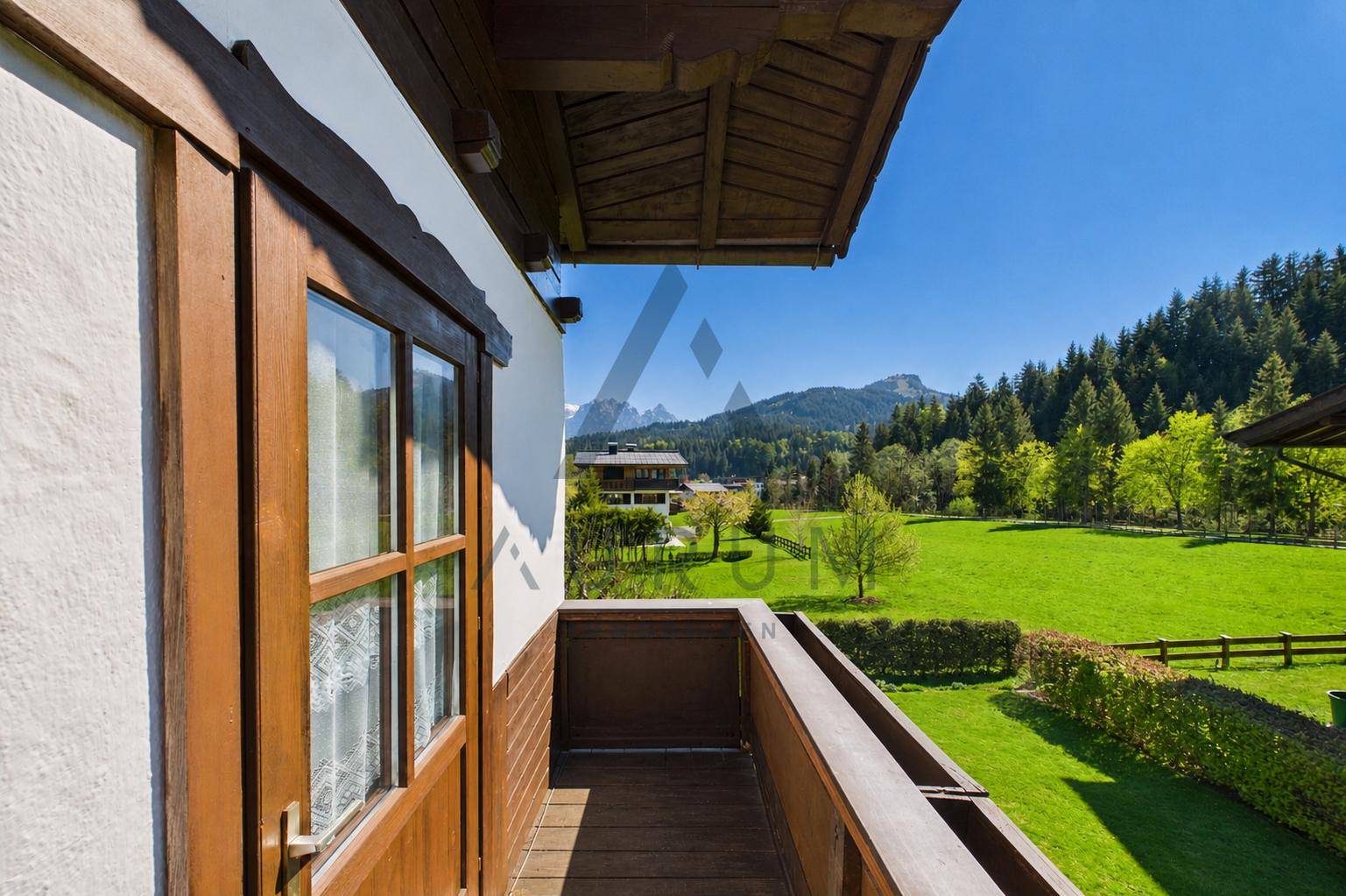Kleiner Holzbalkon mit malerischem Blick auf die grüne Landschaft und die Berge.