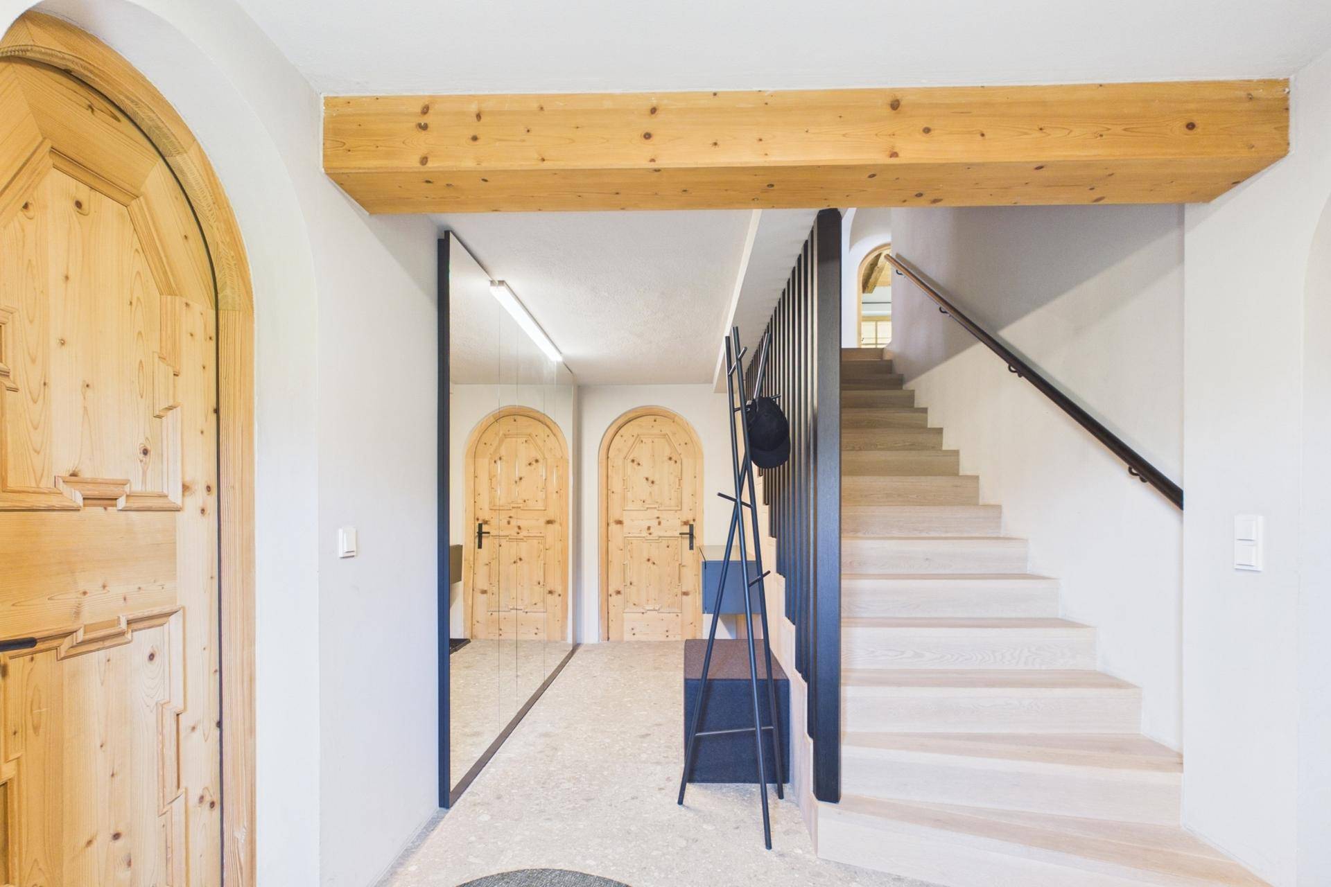 Heller Flur mit Holztreppe, Holztüren und modernem Design.