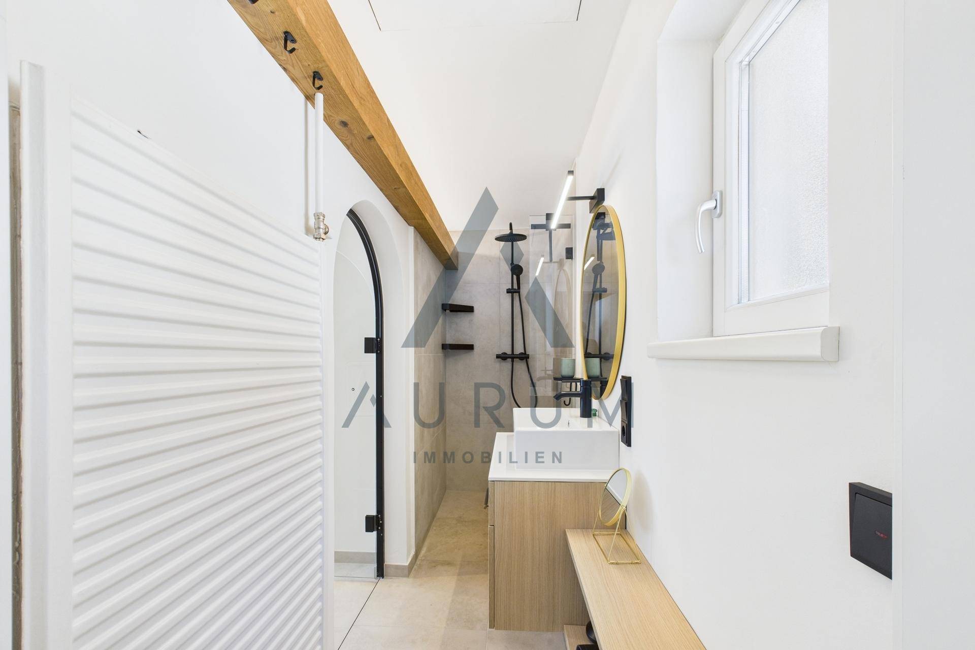 Elegantes Badezimmer mit begehbarer Dusche, modernem Waschtisch und Holzbalken.
