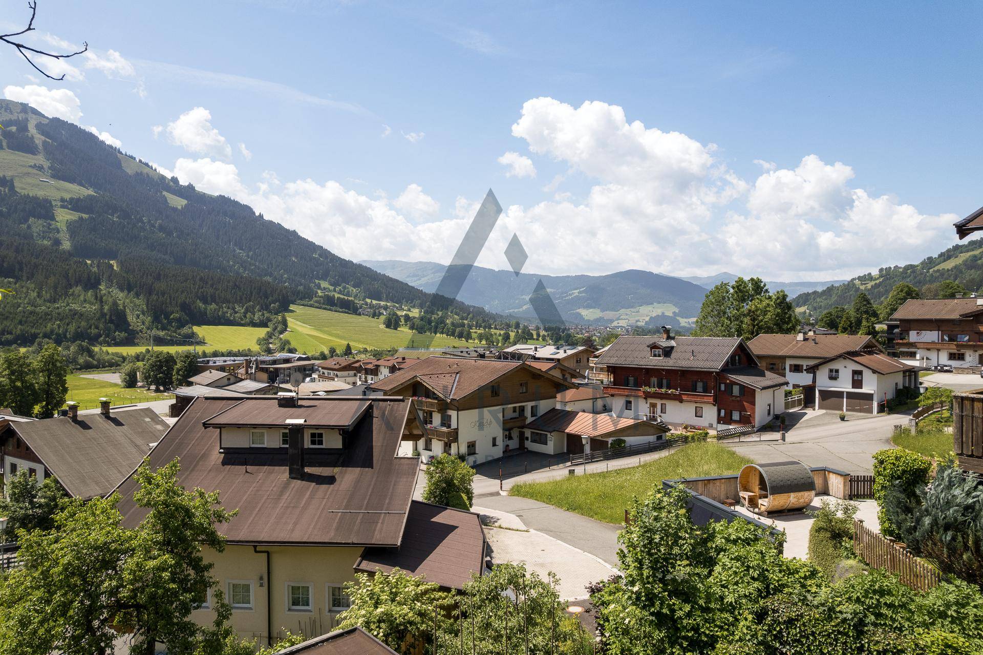 Panoramablick auf eine idyllische Berglandschaft mit einem Dorf und weiten grünen Tälern.