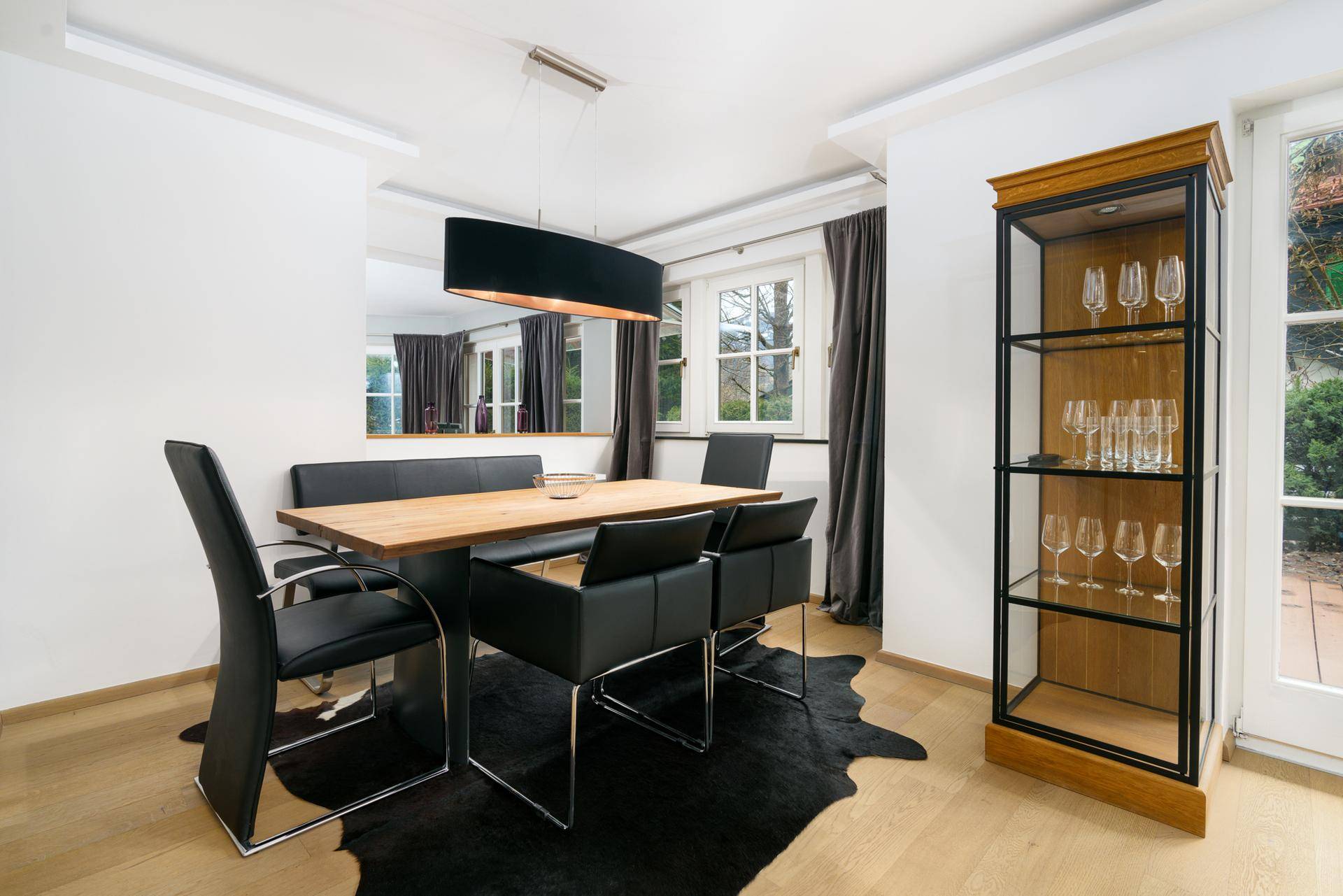 Eleganter Essbereich mit modernem Holztisch, schwarzen Stühlen und Zugang zum Außenbereich.
