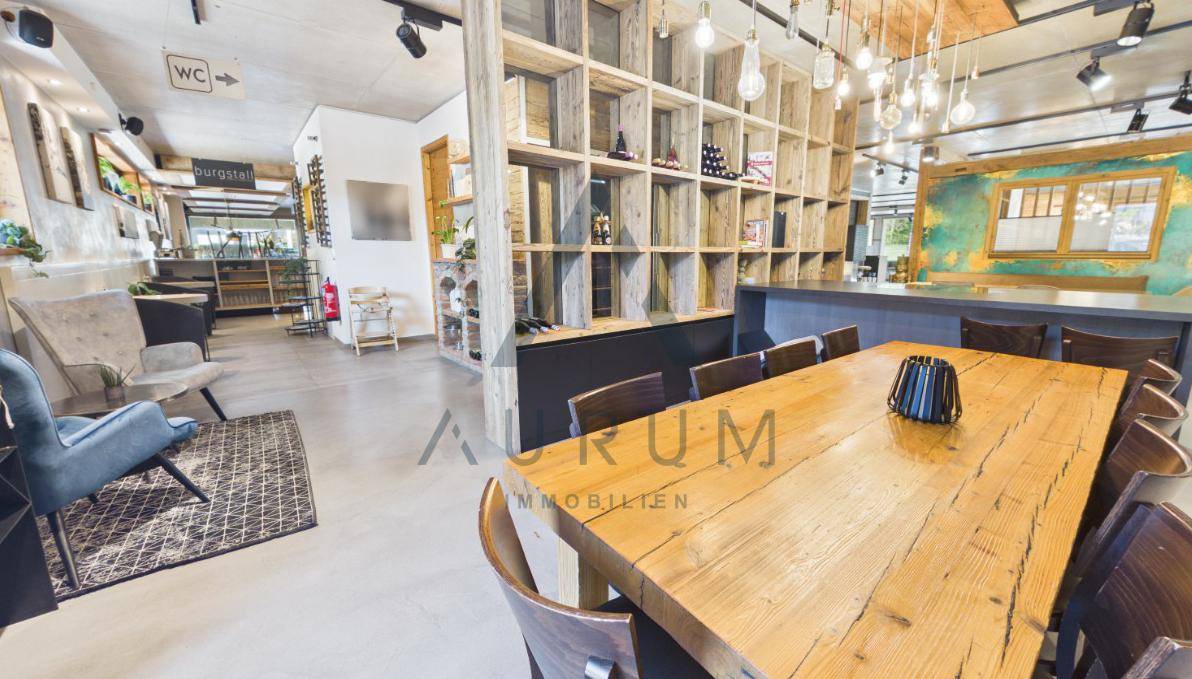 Großer Speisesaal oder Veranstaltungsraum mit langem Holztisch, Stühlen und einer beeindruckenden Holzregalwand.