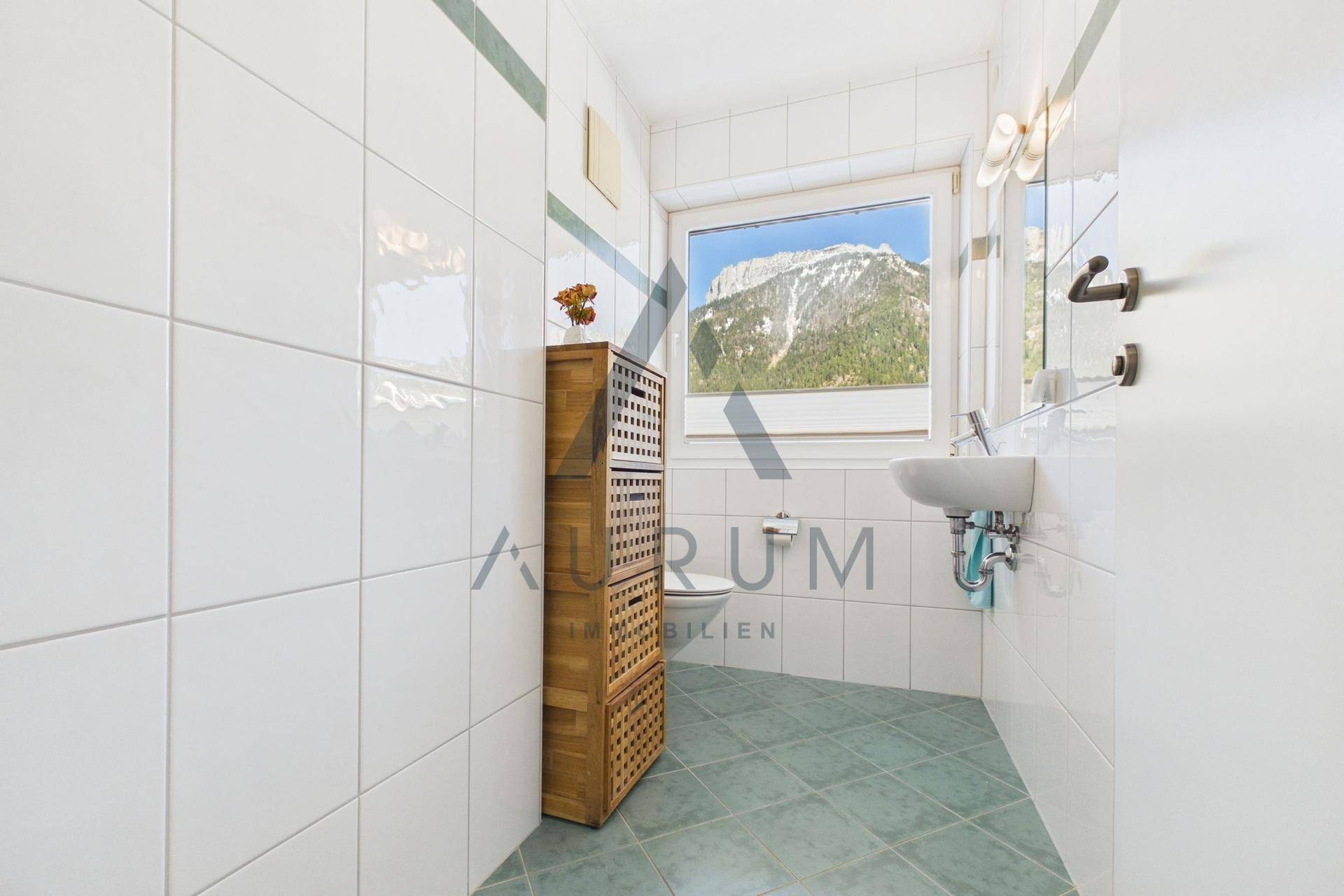 Kleines Gäste-WC mit Fenster, Waschbecken und WC, hell gefliest.