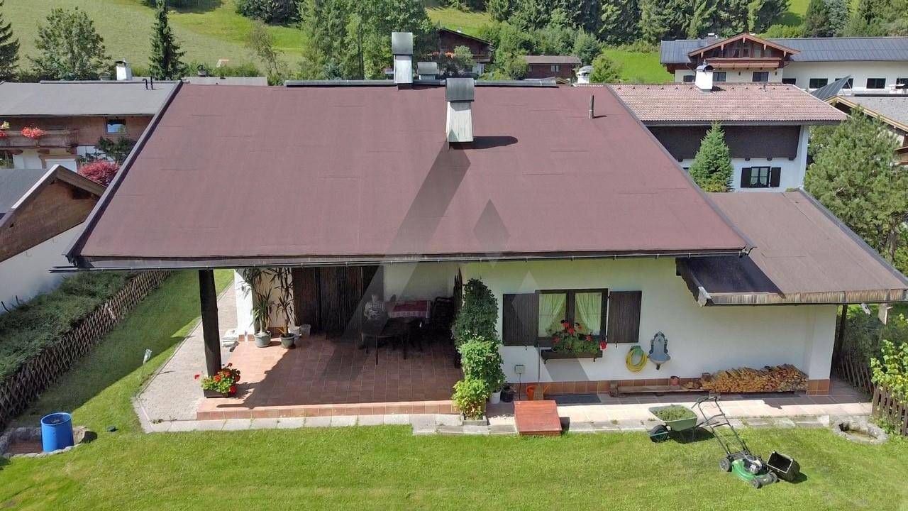 Draufsicht auf das Haus mit großem Garten, Terrasse und dem charakteristischen braunen Satteldach.