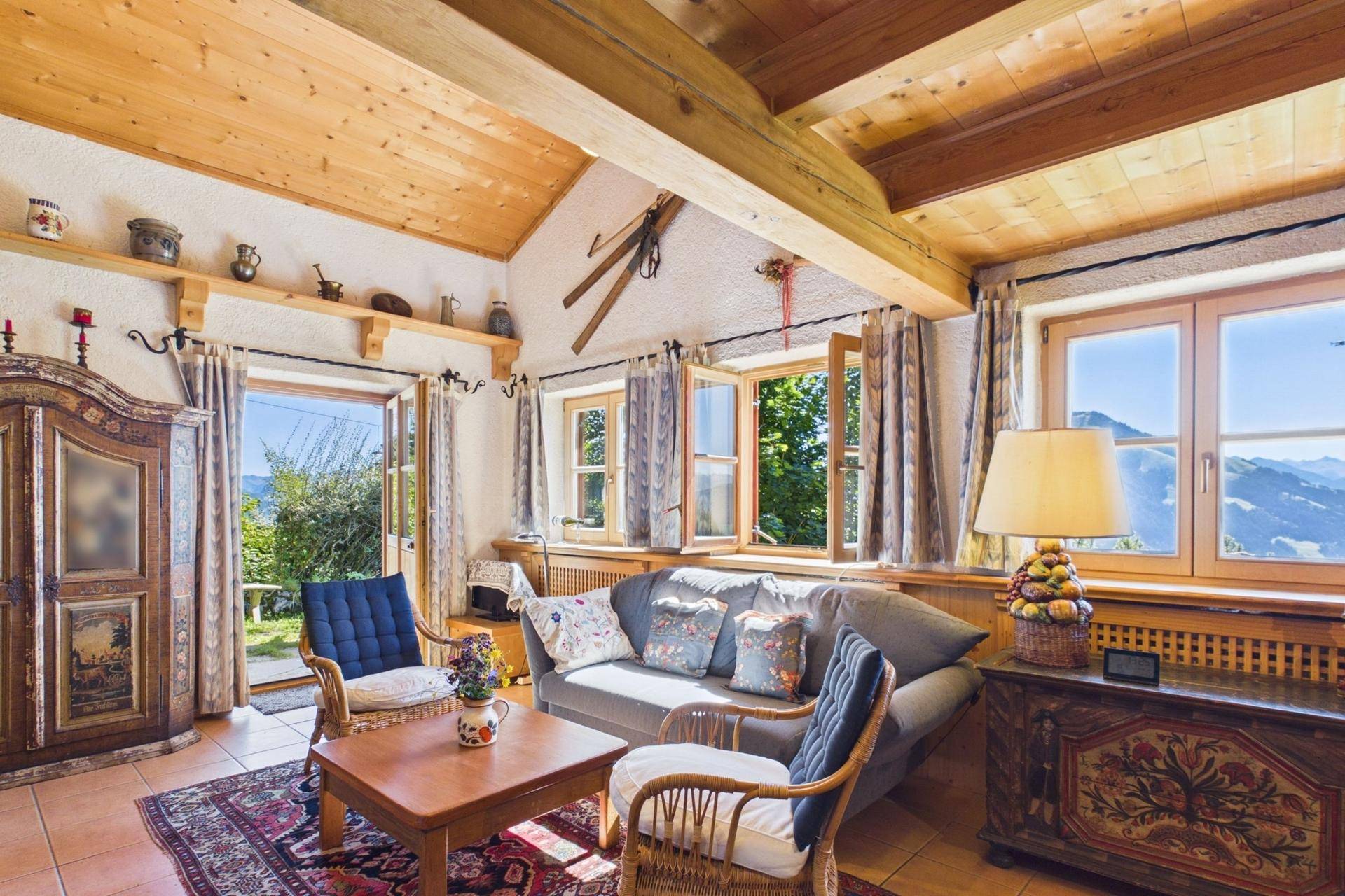 Helles Wohnzimmer mit Holzbalkendecke, traditionellen Möbeln und Bergblick.