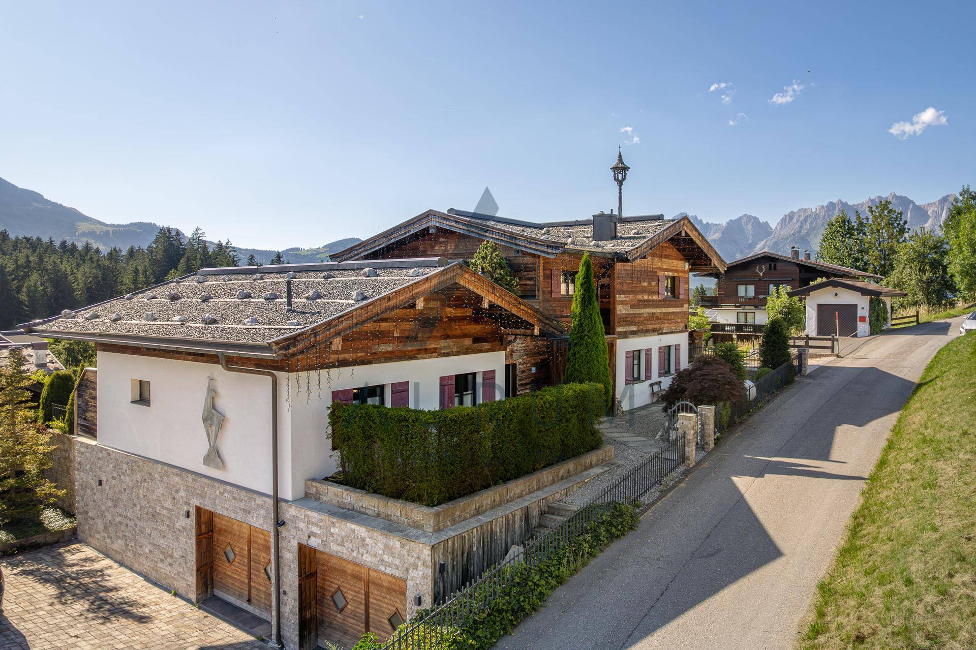 Charmantes Chalet mit Steinfassade, Holzelementen und Doppelgarage in alpiner Landschaft.