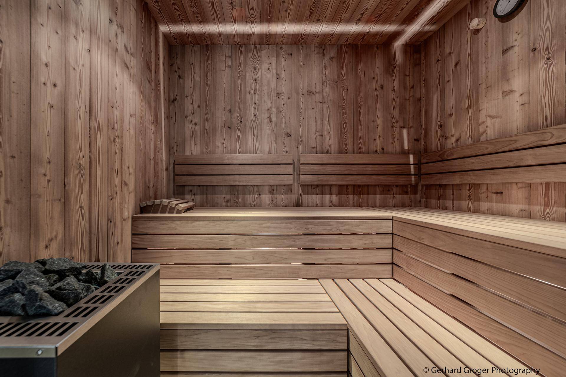 Traditionelle Holzsauna mit mehreren Sitzebenen und einem Saunaofen für entspannende Momente.