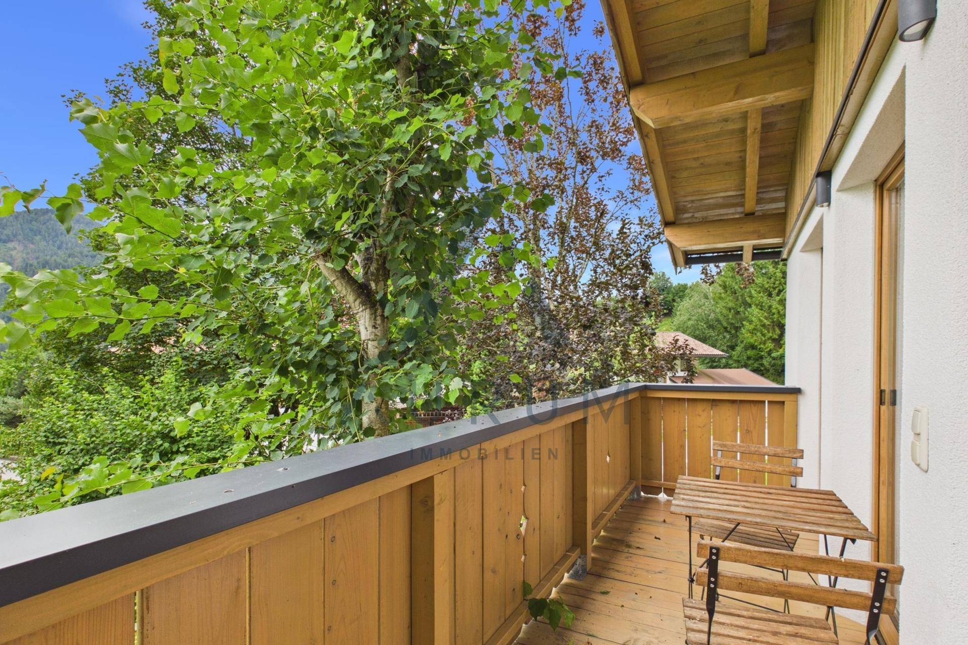 Gemütlicher Holzbalkon mit Sitzgelegenheiten und Blick ins Grüne.