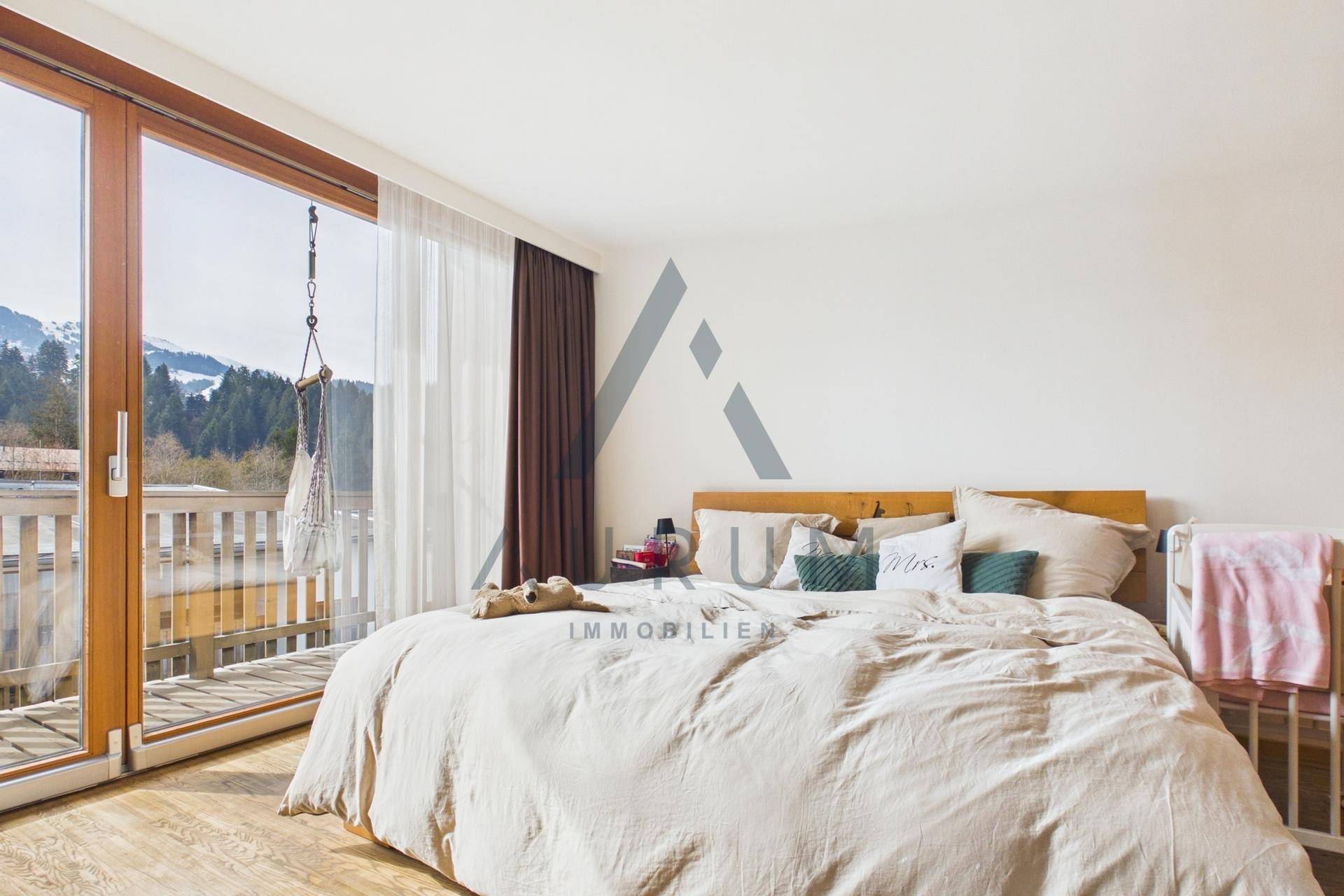 Geräumiges Schlafzimmer mit Bergblick und direktem Zugang zum Balkon durch große Glasfenster.