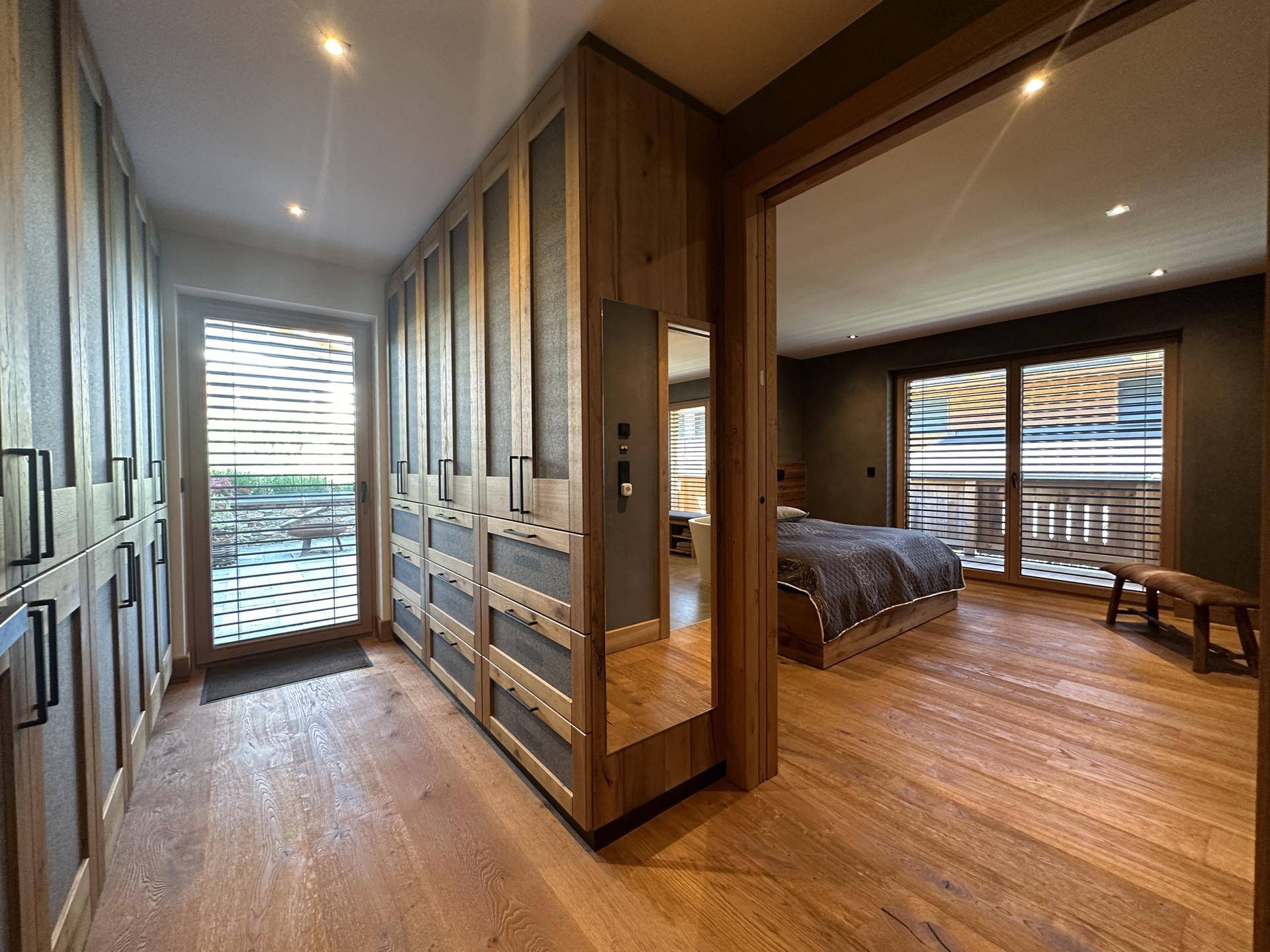 Schlafzimmer mit Holzboden, Einbauschränken und Zugang zu einem Außenbereich.