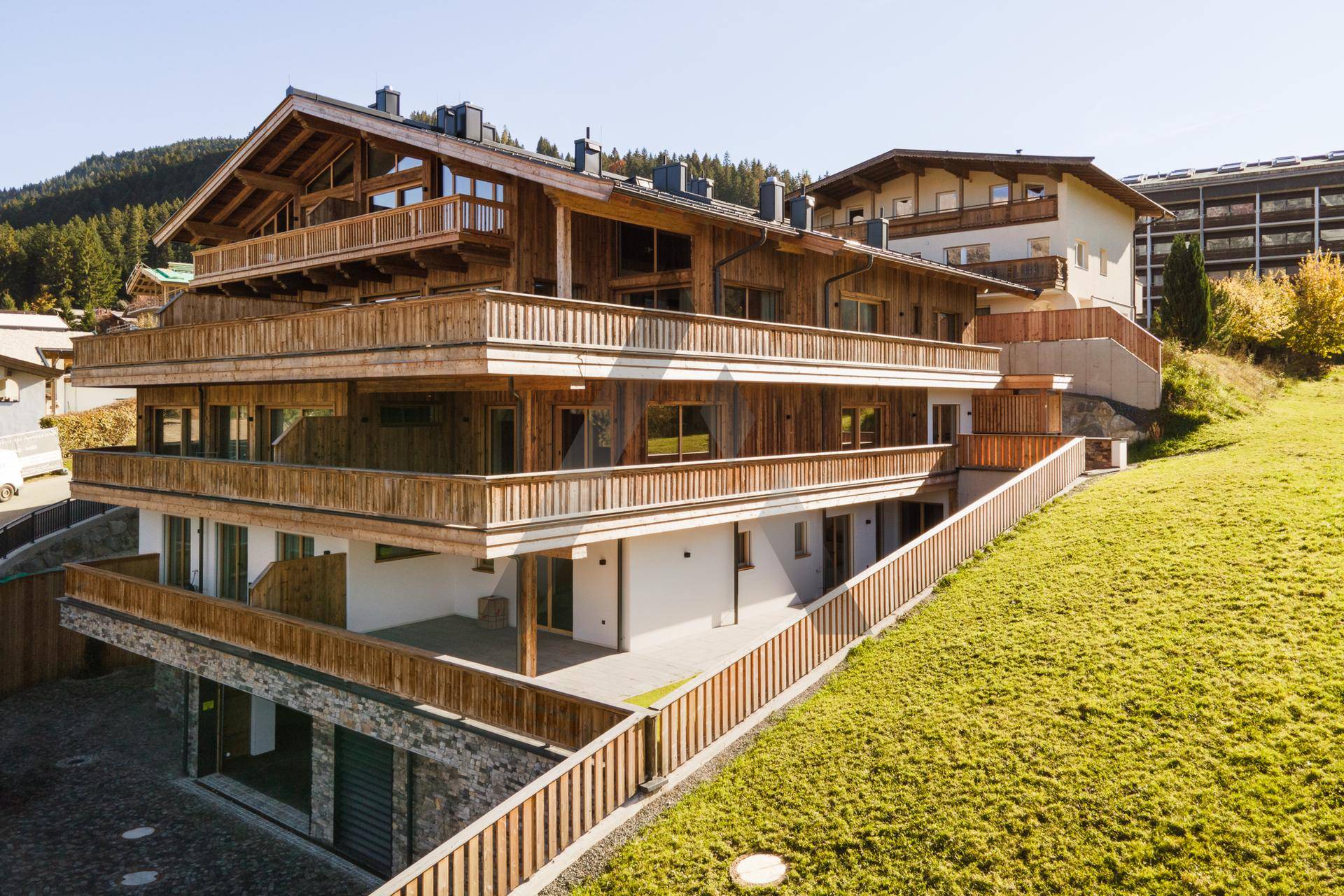 Modernes Holzhaus in Hanglage mit mehreren Balkonen und Terrassenbereichen.
