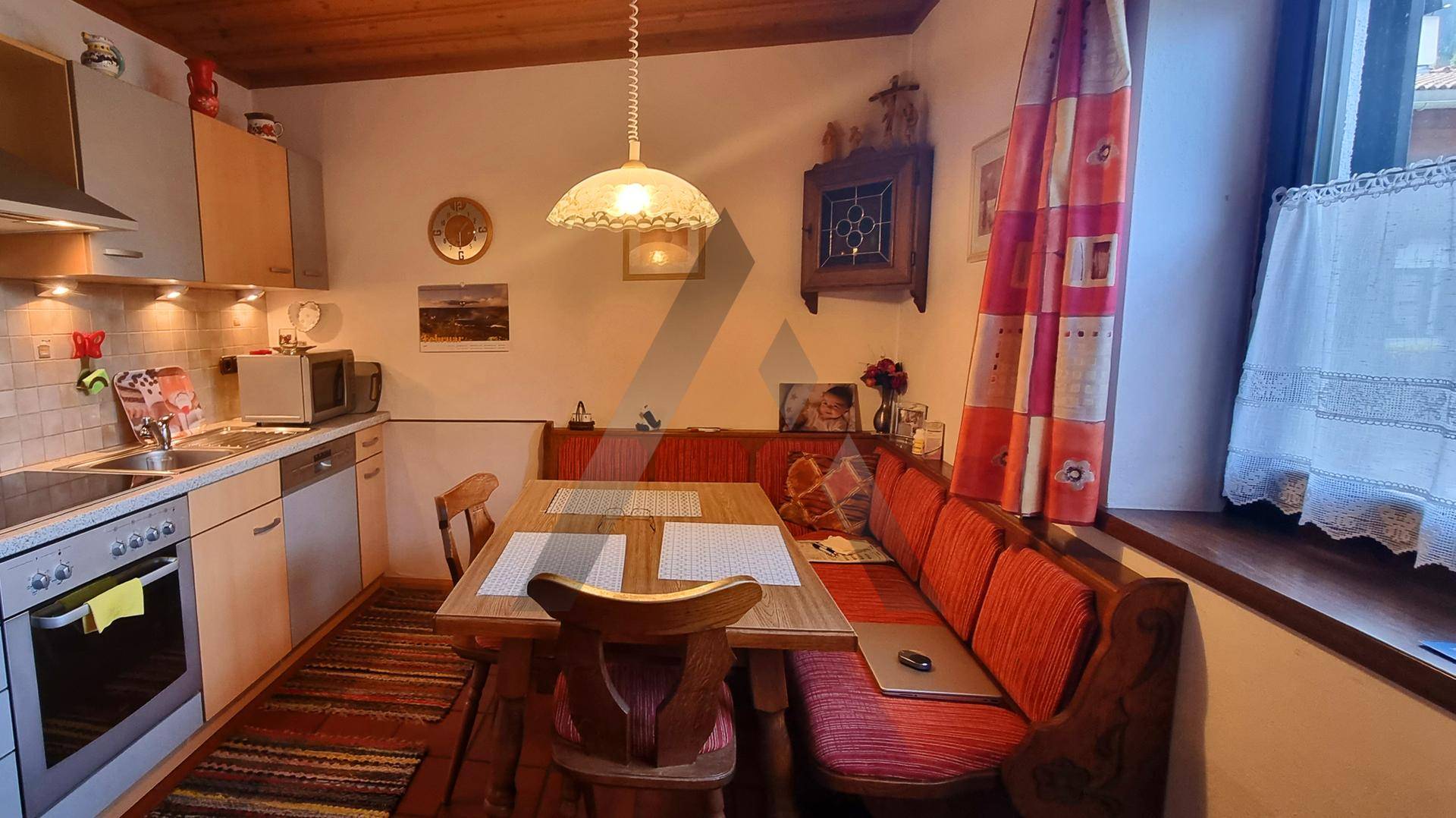 Funktionale Küche mit integriertem Essbereich, Holzmöbeln und einem Fenster für natürliches Licht.