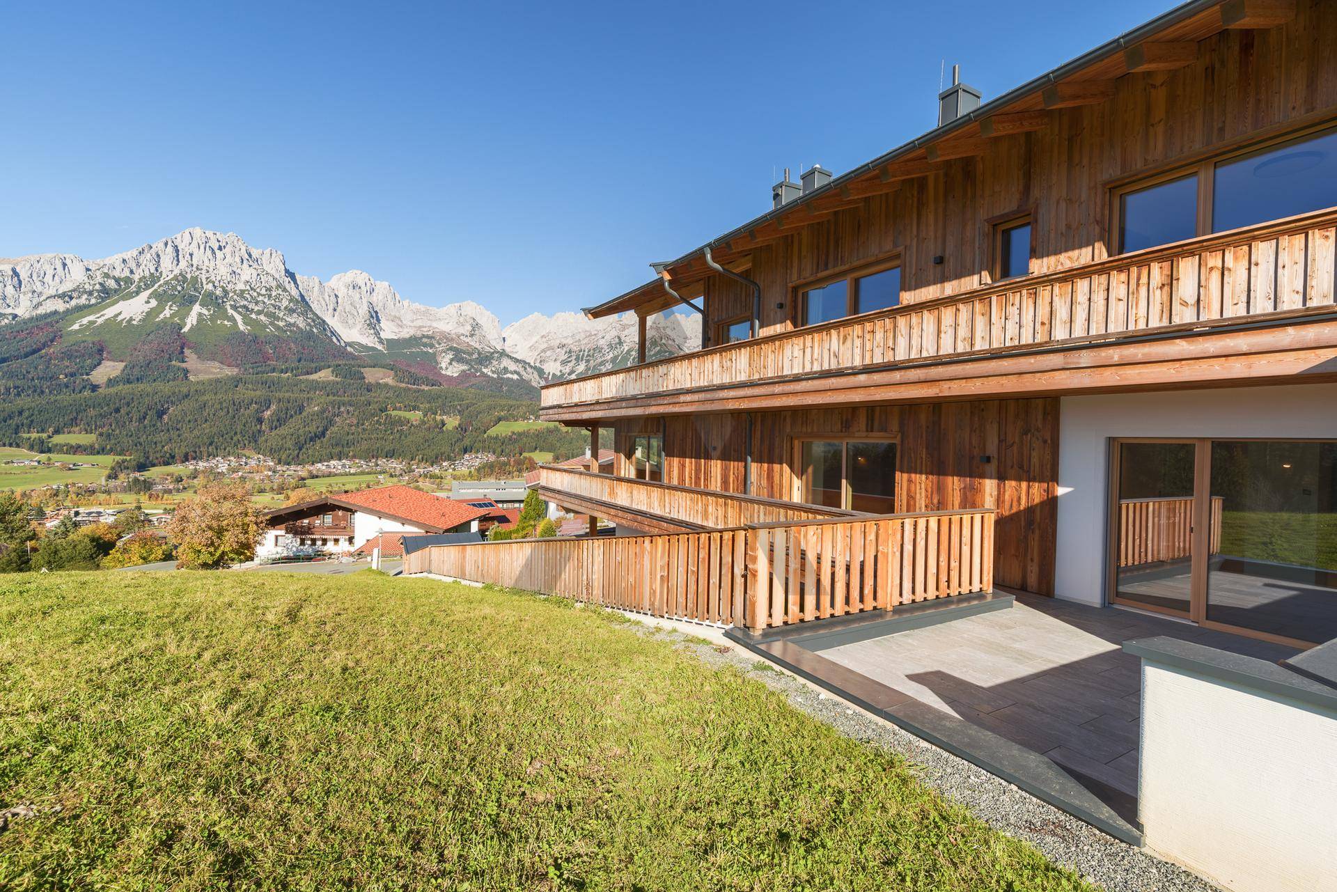 Attraktives Holzhaus in Hanglage mit mehreren Balkonen und Bergblick.