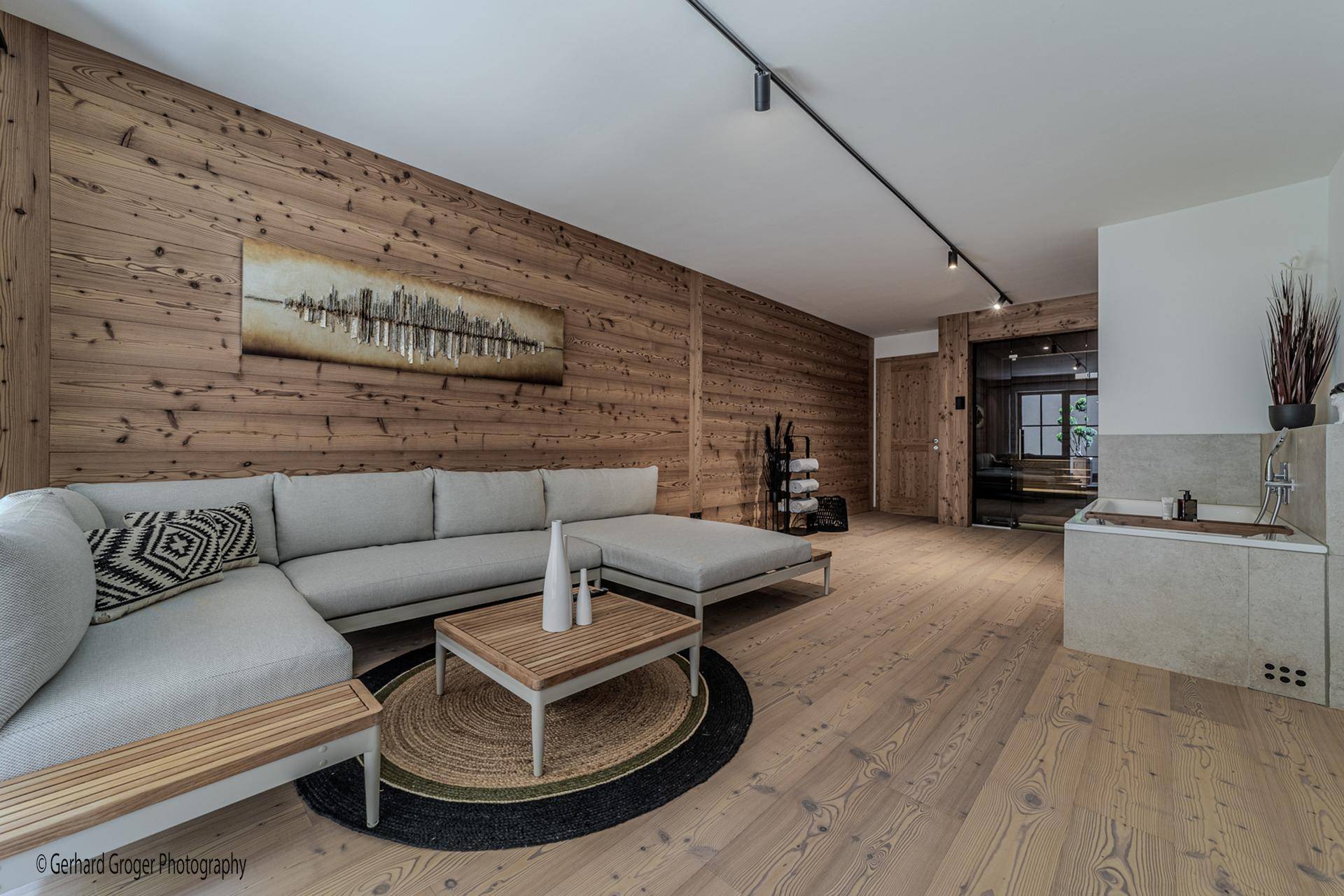 Entspannungsbereich mit bequemer Couch, Holzwand und Blick auf den Wellnessbereich.