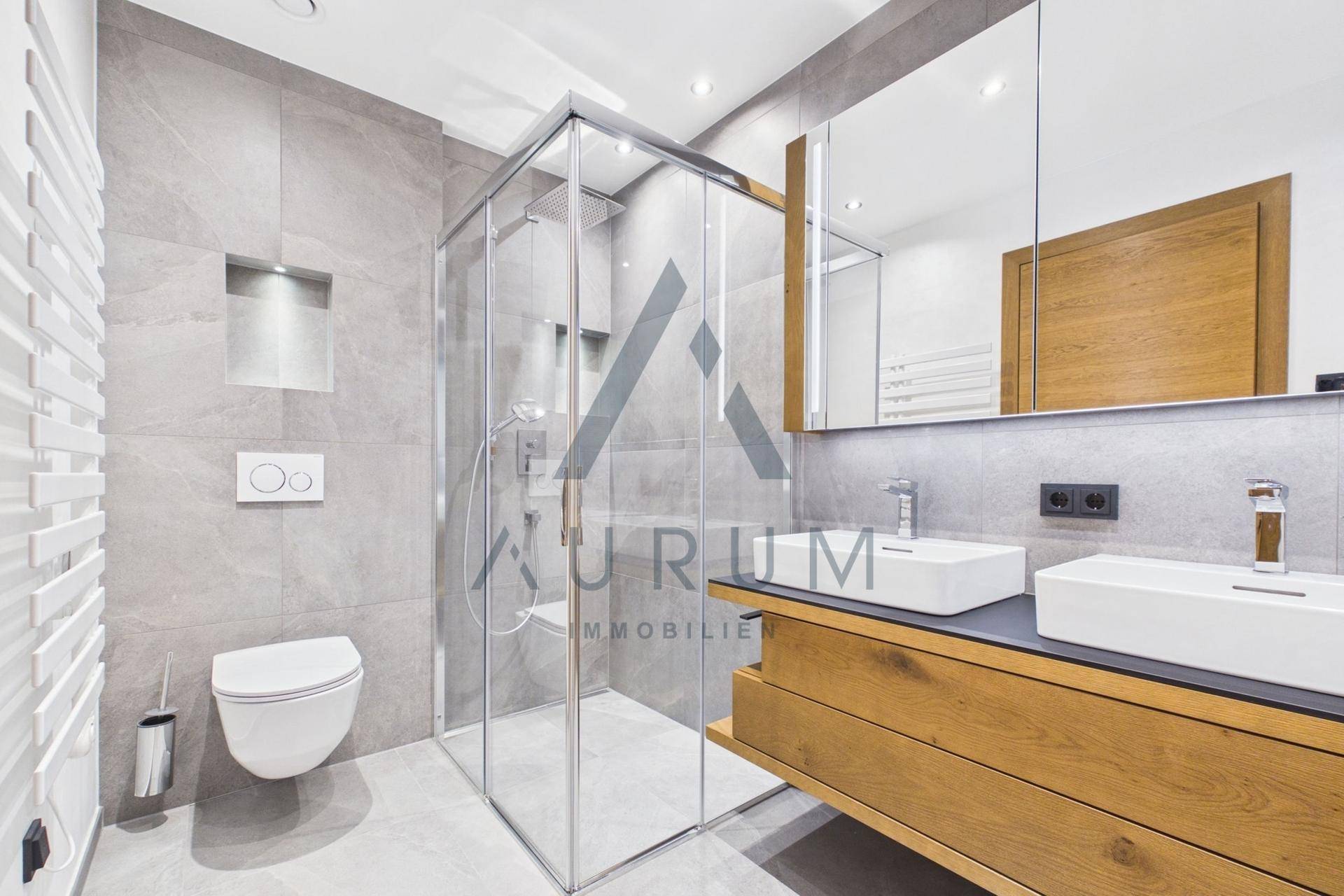Elegantes Badezimmer mit begehbarer Dusche, Doppelwaschbecken und wandhängendem WC, modern gefliest.