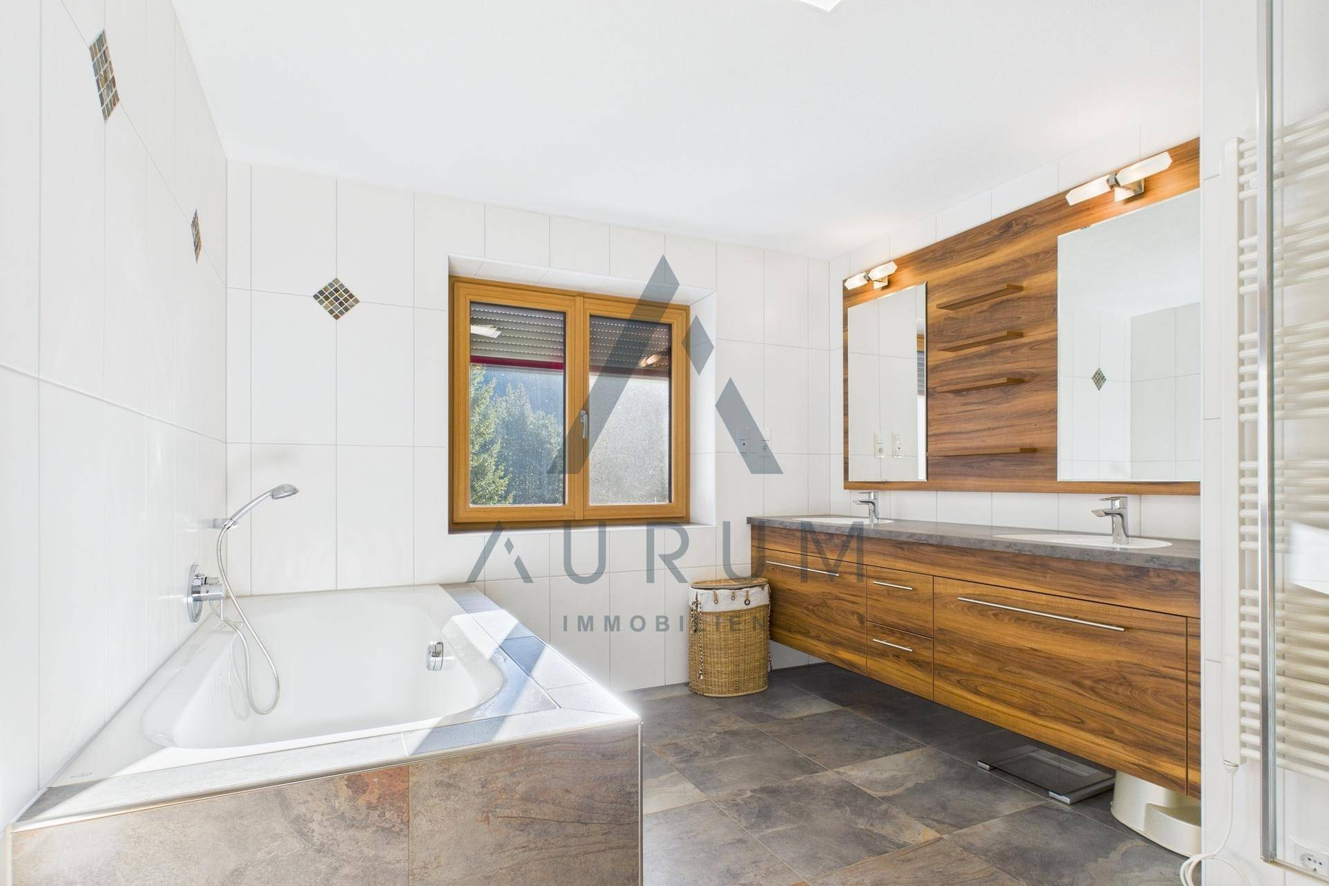 Großes Badezimmer mit Doppelwaschbecken, Eckbadewanne und Fenster mit Bergblick.