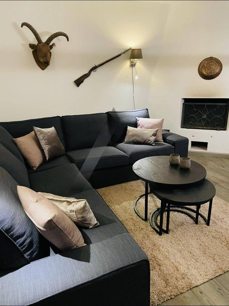 Gemütliches Wohnzimmer mit Ecksofa, Kamin und rustikalen Dekorationen.