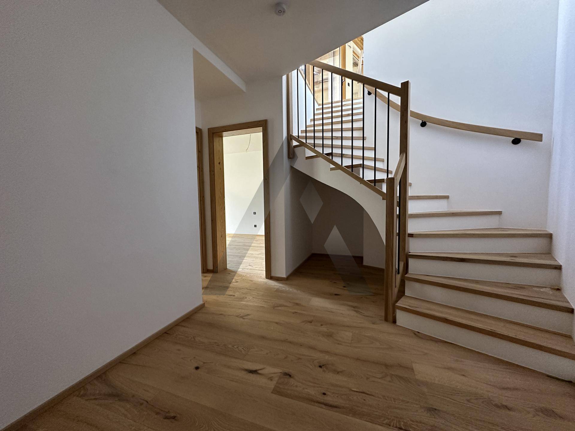 Elegante Holztreppe mit Metallgeländer, die verschiedene Ebenen des Hauses verbindet.
