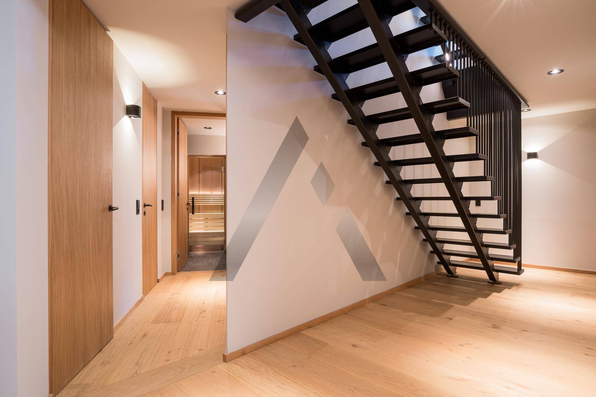 Heller Flur mit Holzboden und einer modernen schwarzen Treppe, die in die obere Etage führt.